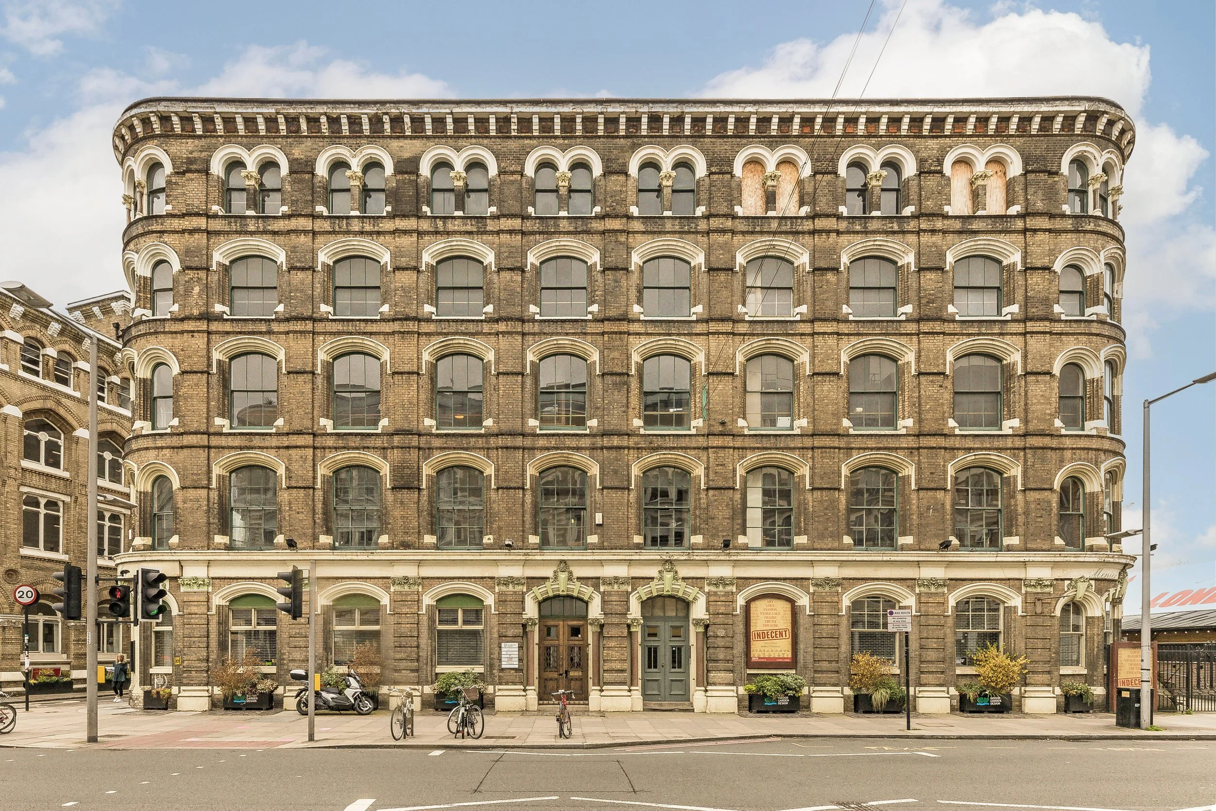 Historic brick building with arched windows and a decorative entrance on a city street.