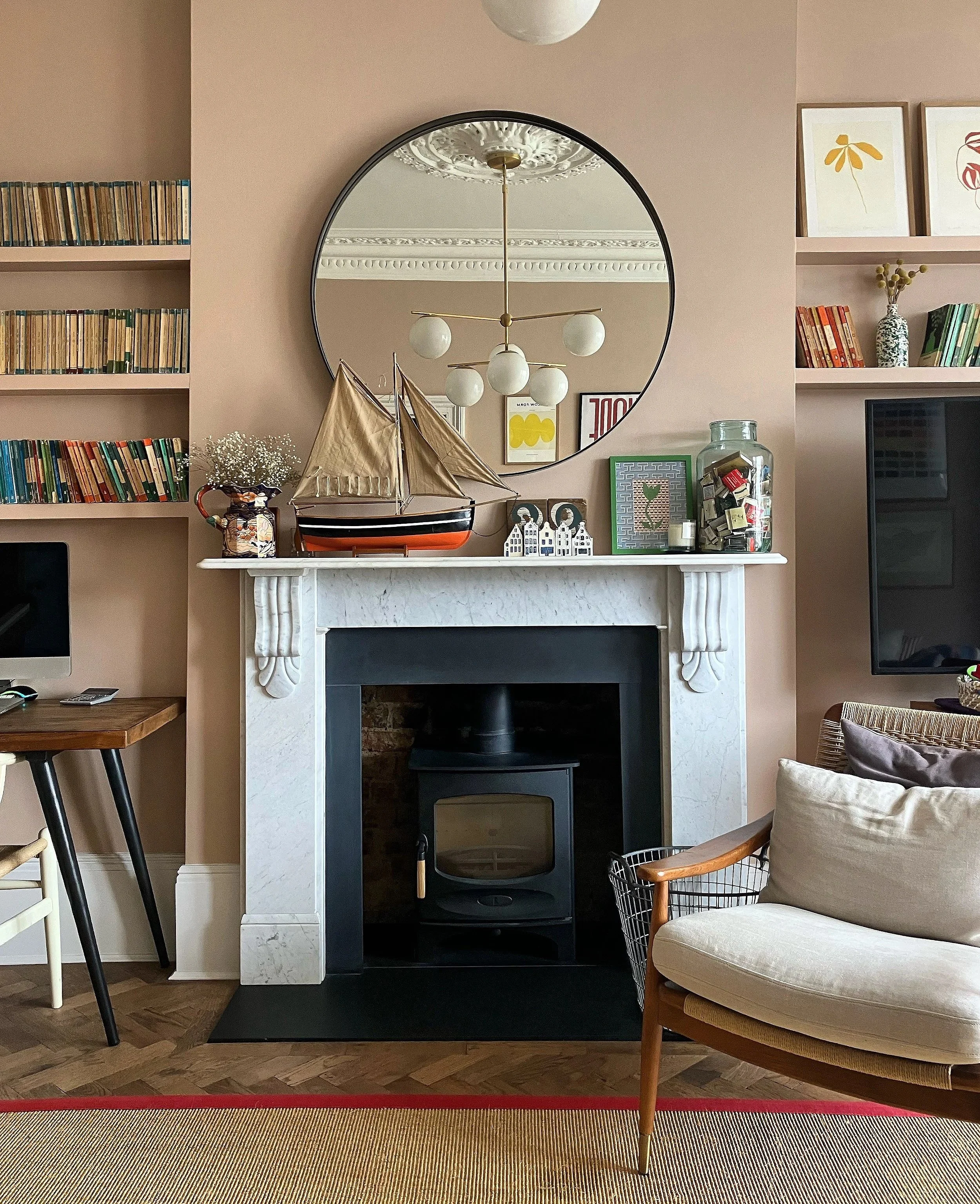 Living room with a fireplace, mirror, model sailboat, books, and art decor.