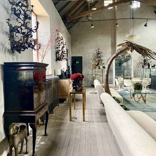 Elegant interior of a lounge or boutique space with vintage furniture, floral arrangements, and decorative dried branches.