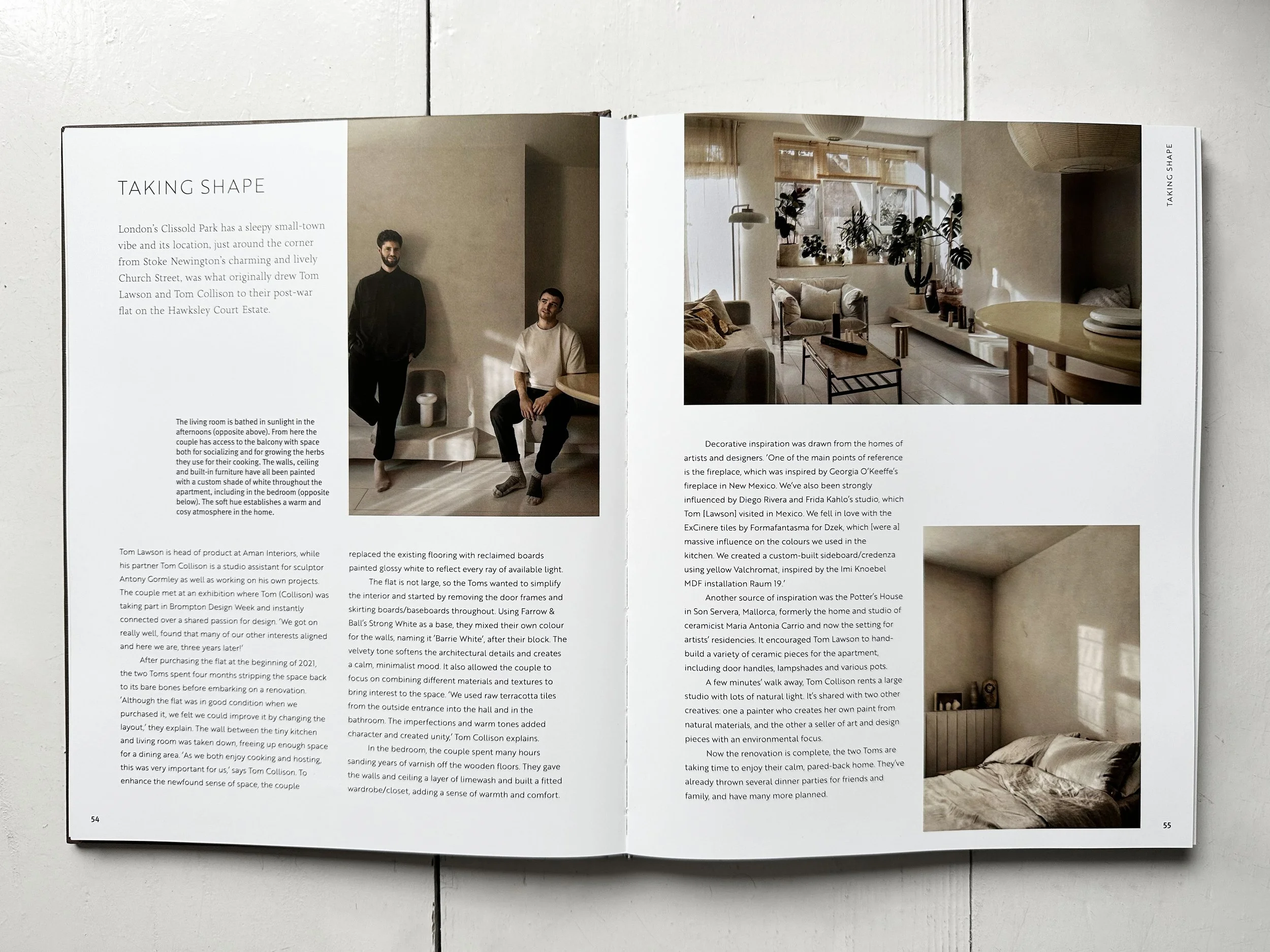 Open magazine spread with text and three photographs of interior spaces, two on the right page and one on the left.