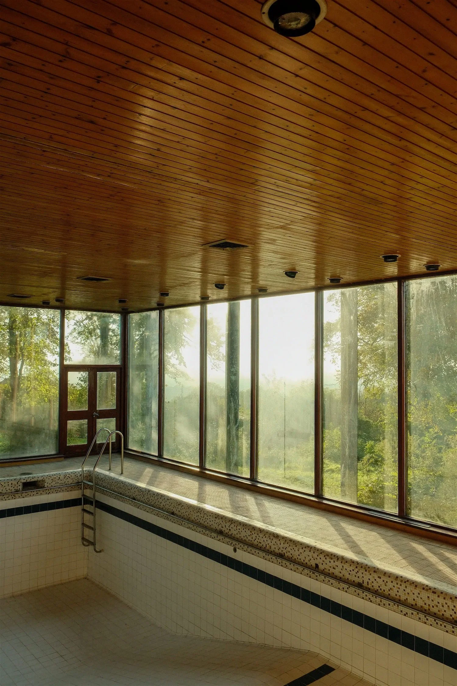 Indoor pool area with large windows, wooden ceiling, and mountain view outside.