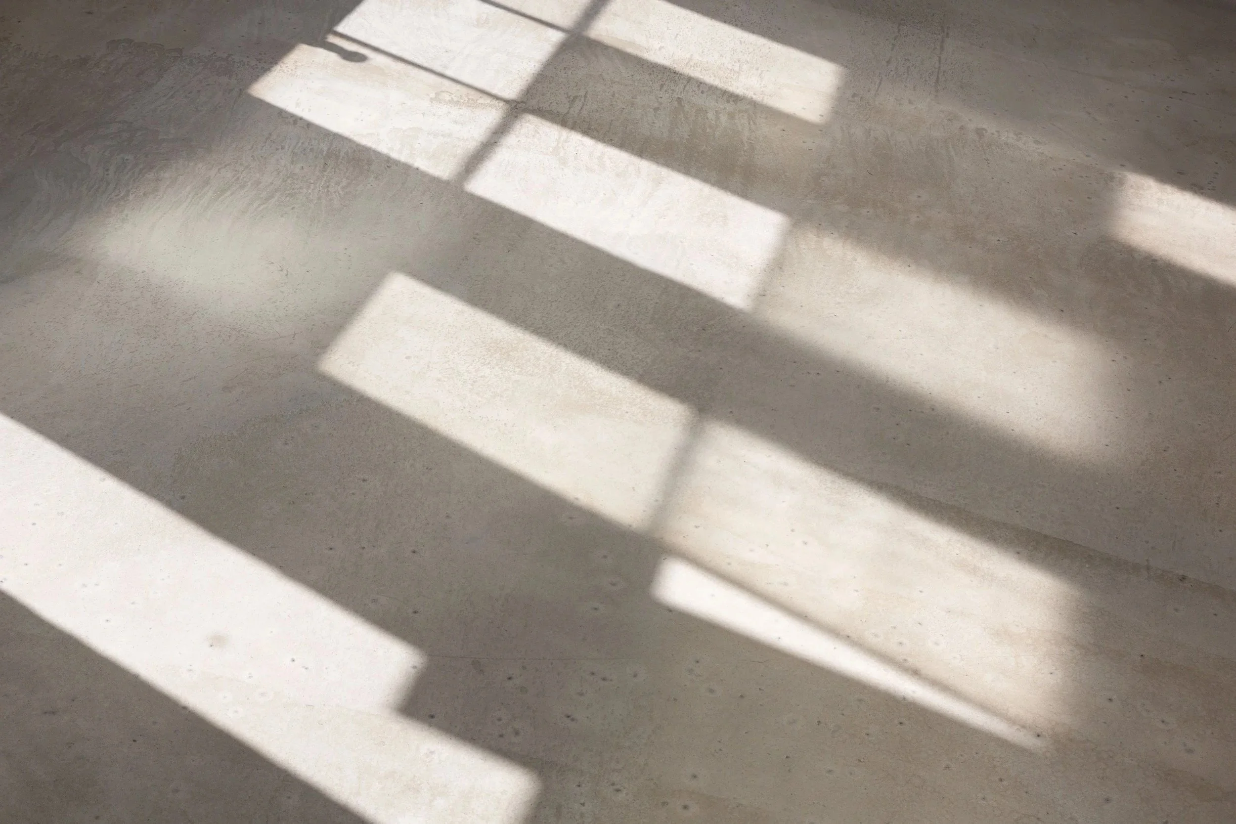 Sunlight casting rectangular shadows on a light-colored textured surface.