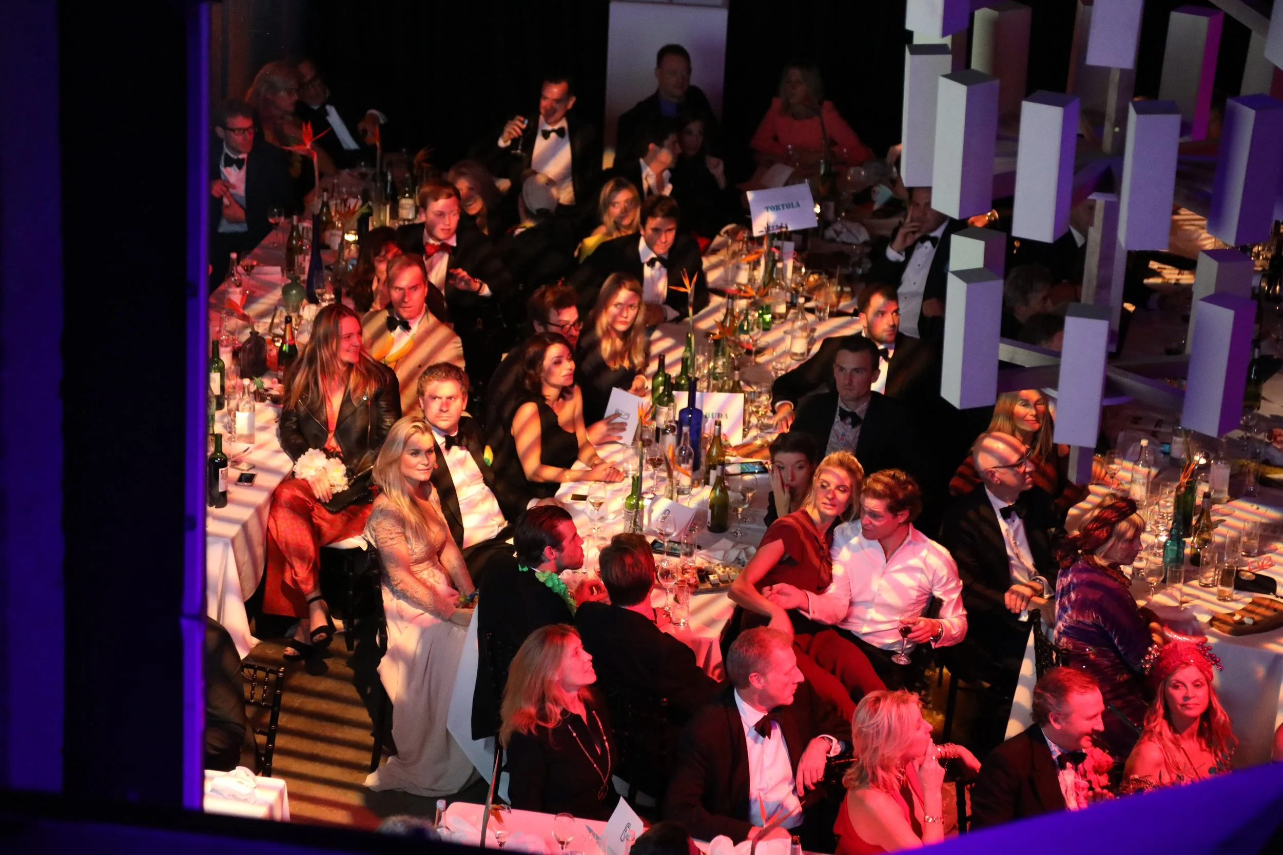 Guests in formal attire seated at tables during a banquet or award ceremony.