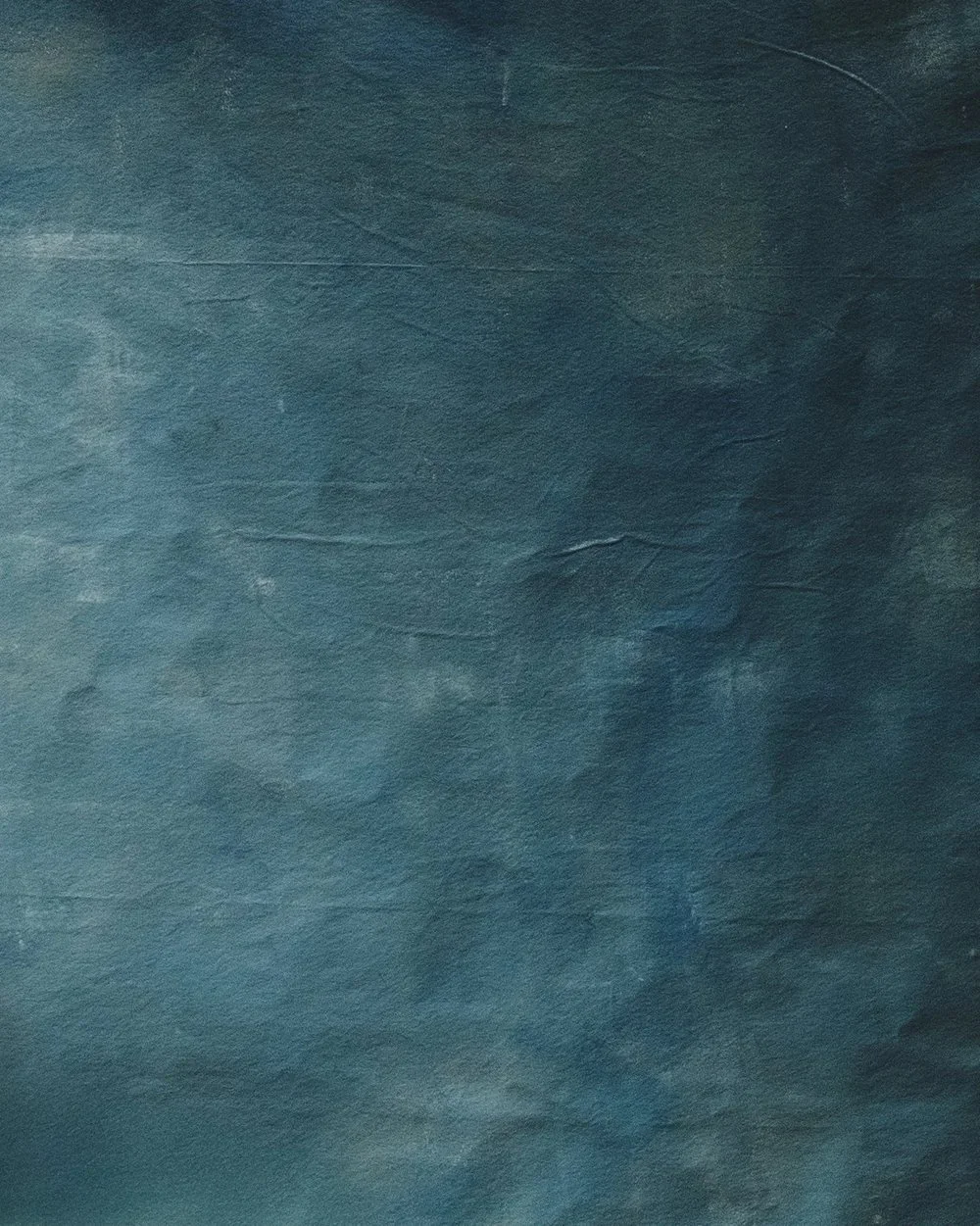 Dark textured surface with bluish-green hues, resembling a leather or painted material.