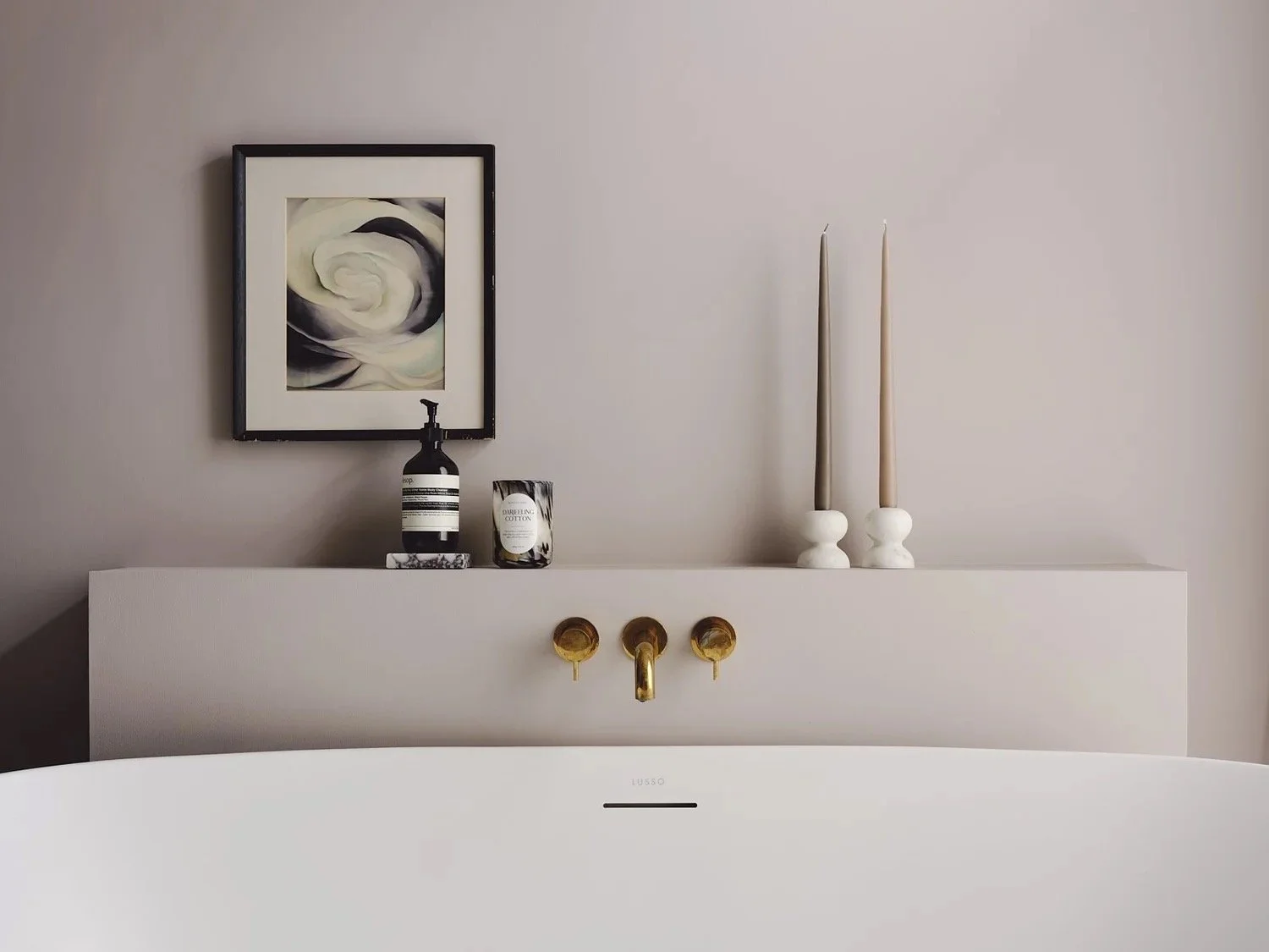 Bathroom sink with a white vanity, a framed abstract black and white artwork on the wall, candles, and a soap dispenser on the countertop, with two tall candles in white holders to the right.