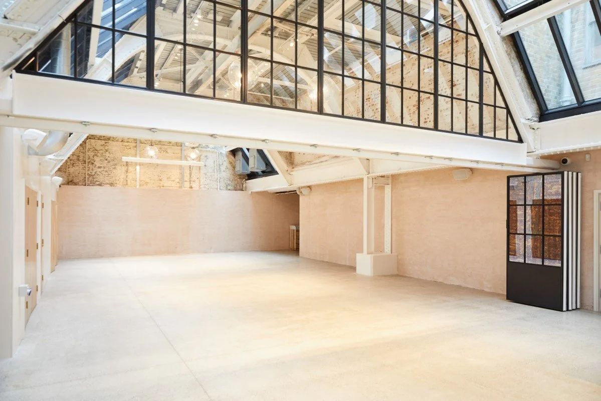 Empty modern loft with exposed brick and large glass windows, high ceilings, and open space.