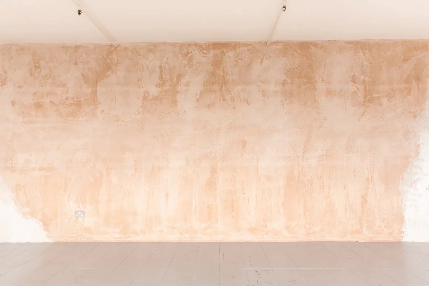 Empty room with unfinished peach-colored wall and a tiled floor.