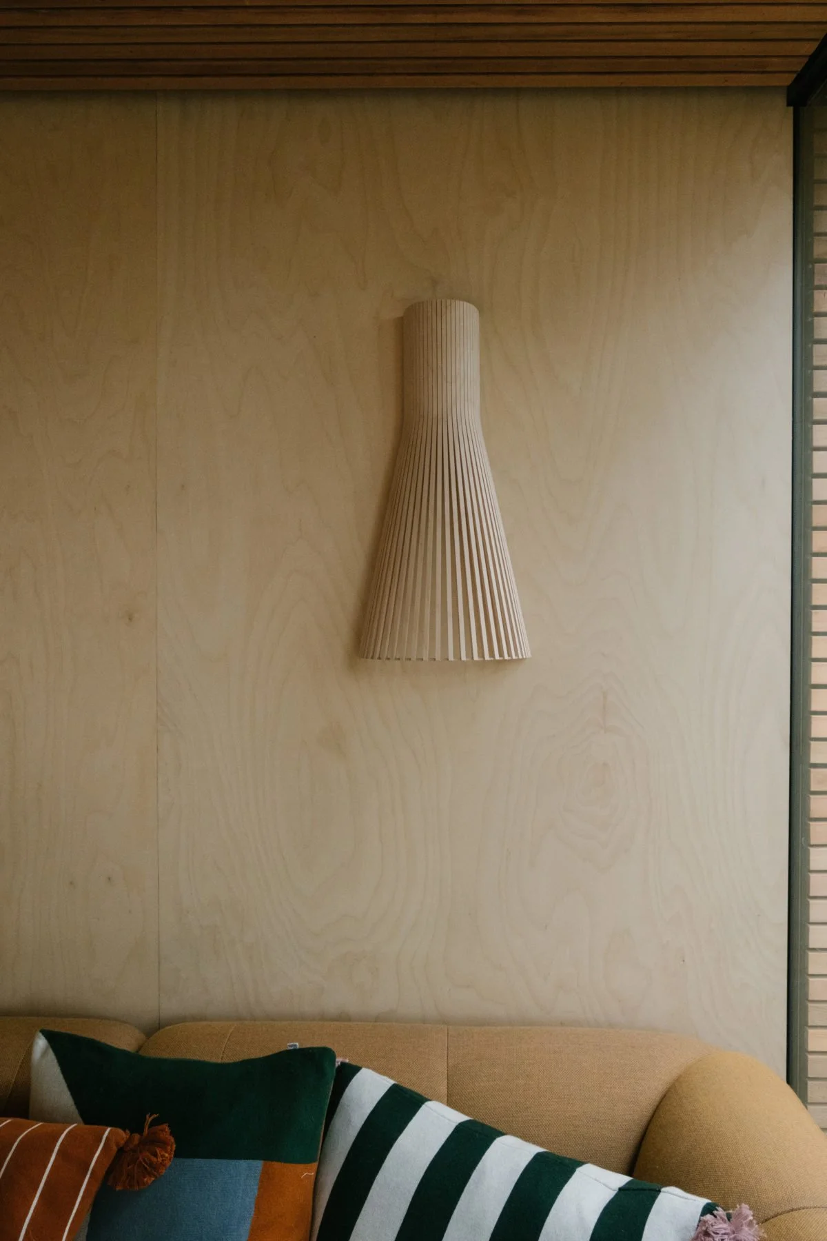 Wooden wall-mounted decorative lamp above a sofa with pillows.