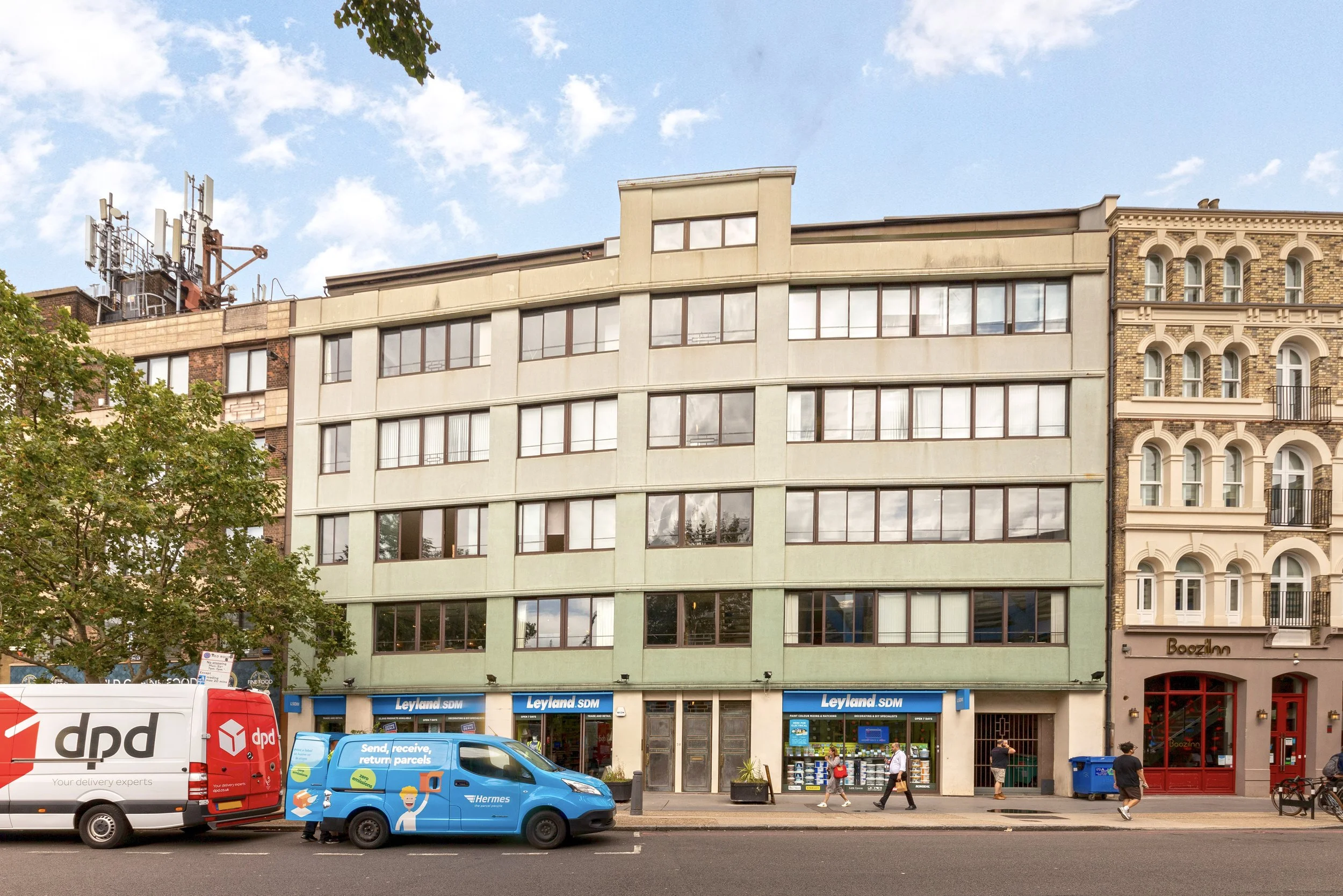 A multi-story building with a storefront at street level and many windows, surrounded by vehicles and pedestrians.