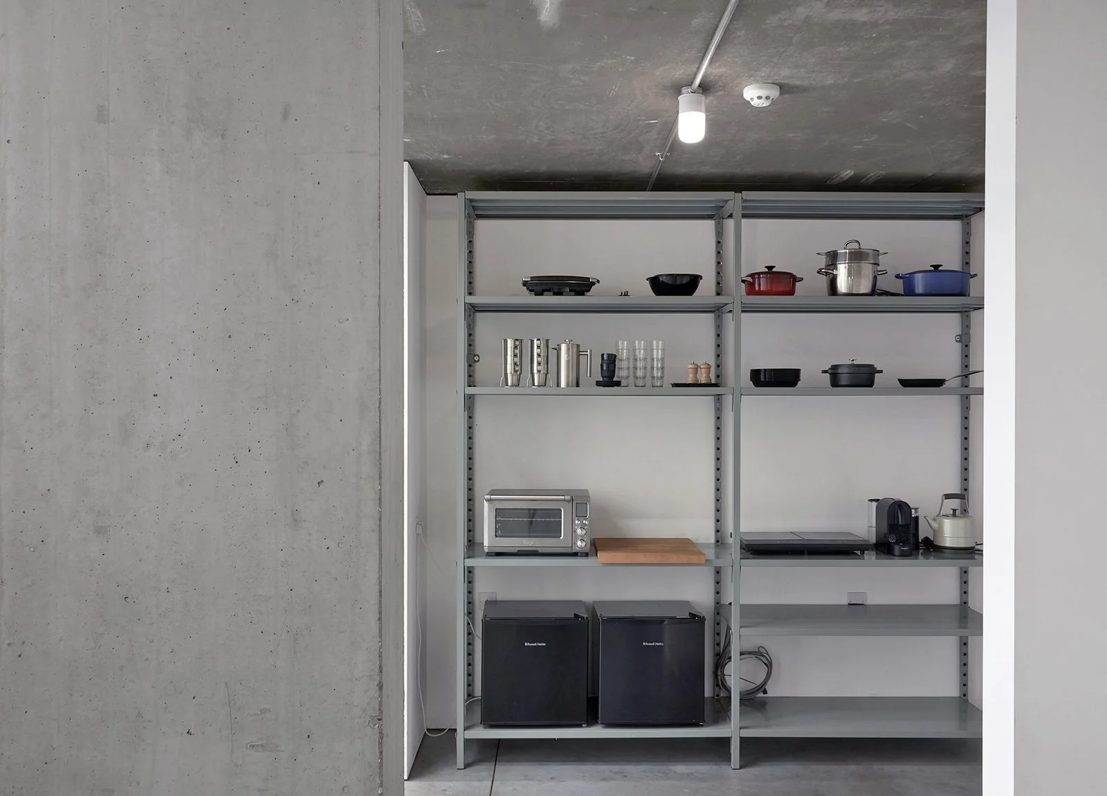 Kitchen with open shelving containing cookware, glasses, and appliances such as microwave, mini fridge, and coffee maker.