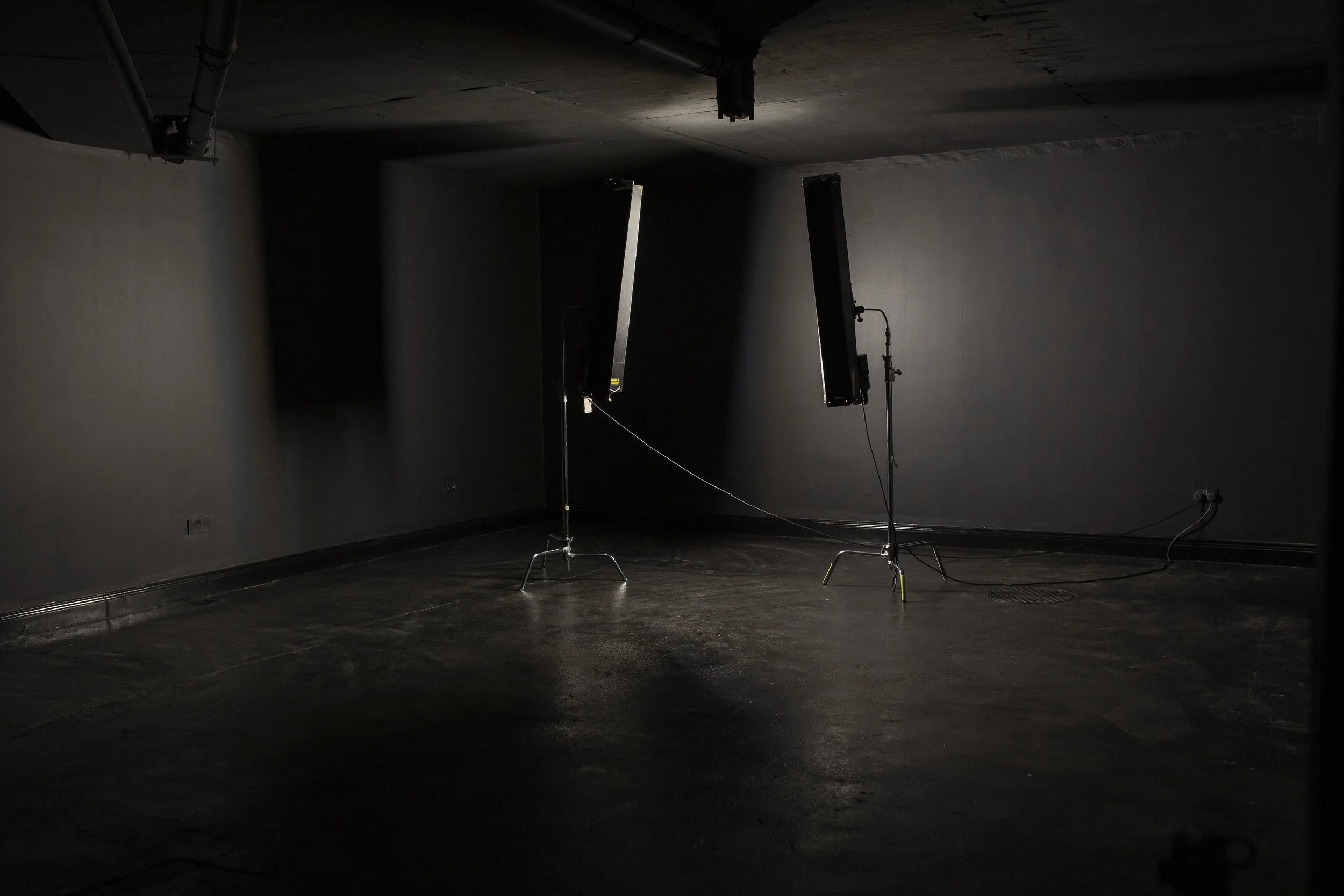 Dark empty room with two studio lights on stands, no people, minimal furnishings