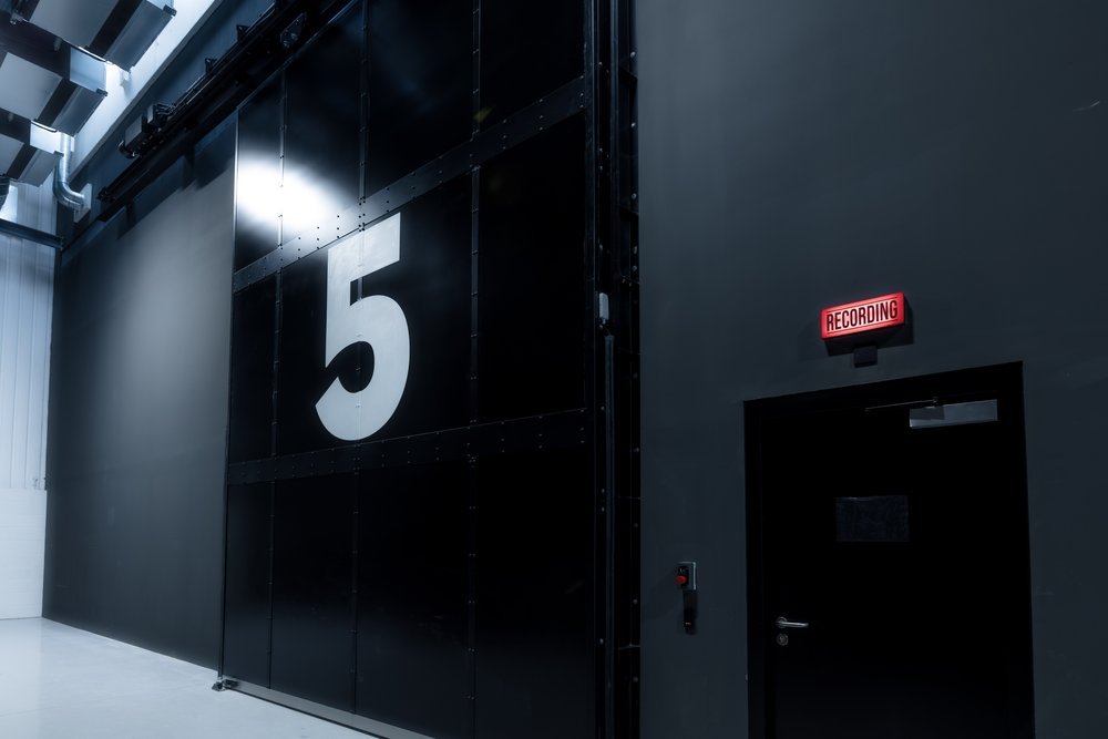 Interior of a recording studio with a black wall, a large white number 5, and a red 'RECORDING' sign above a door.