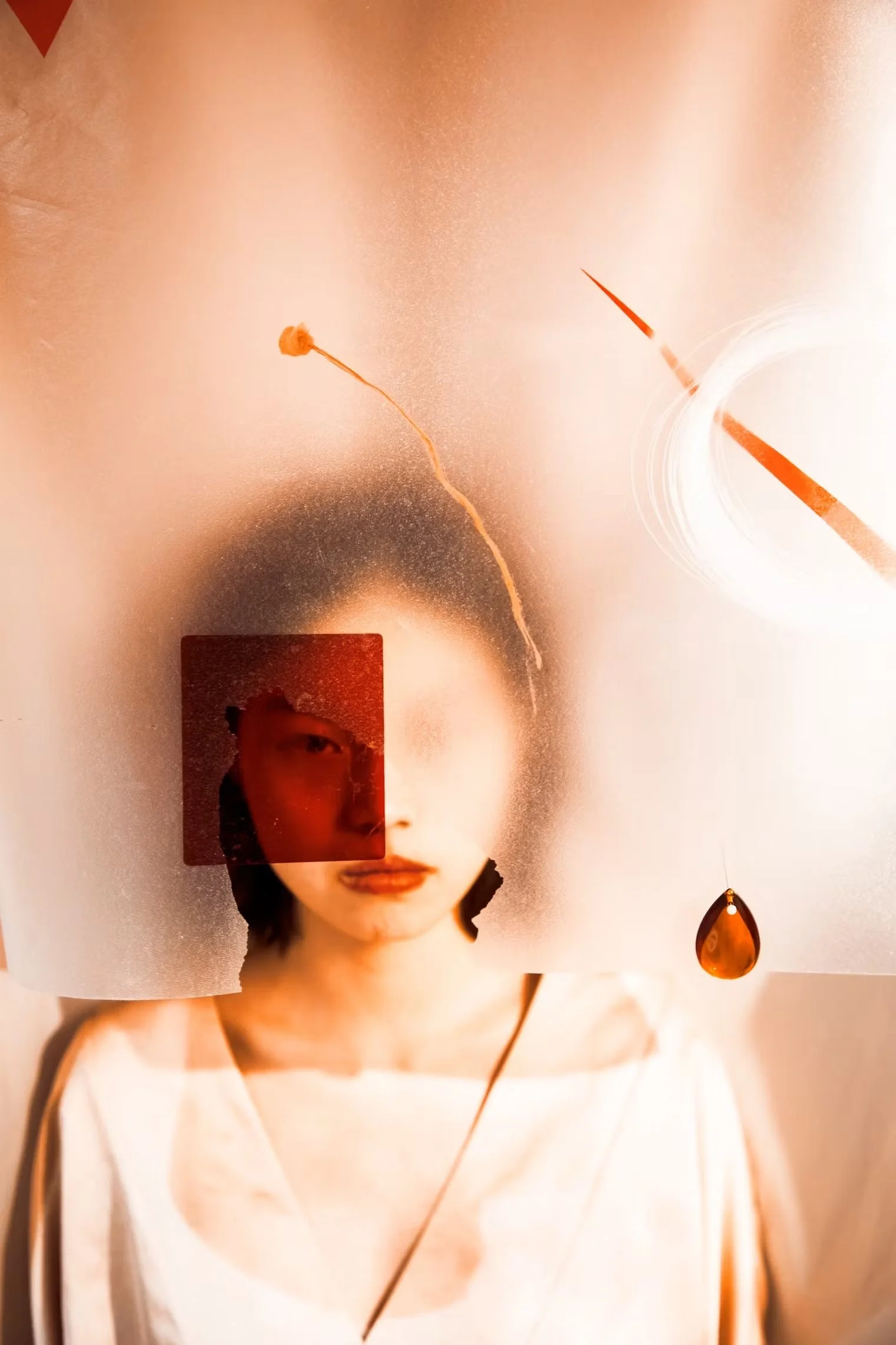 A mixed-media artwork features a woman's face with a photograph of her face superimposed as a red-tinted square over her eye. The background has soft, muted tones with abstract elements including pointed shapes and a tear-shaped object.