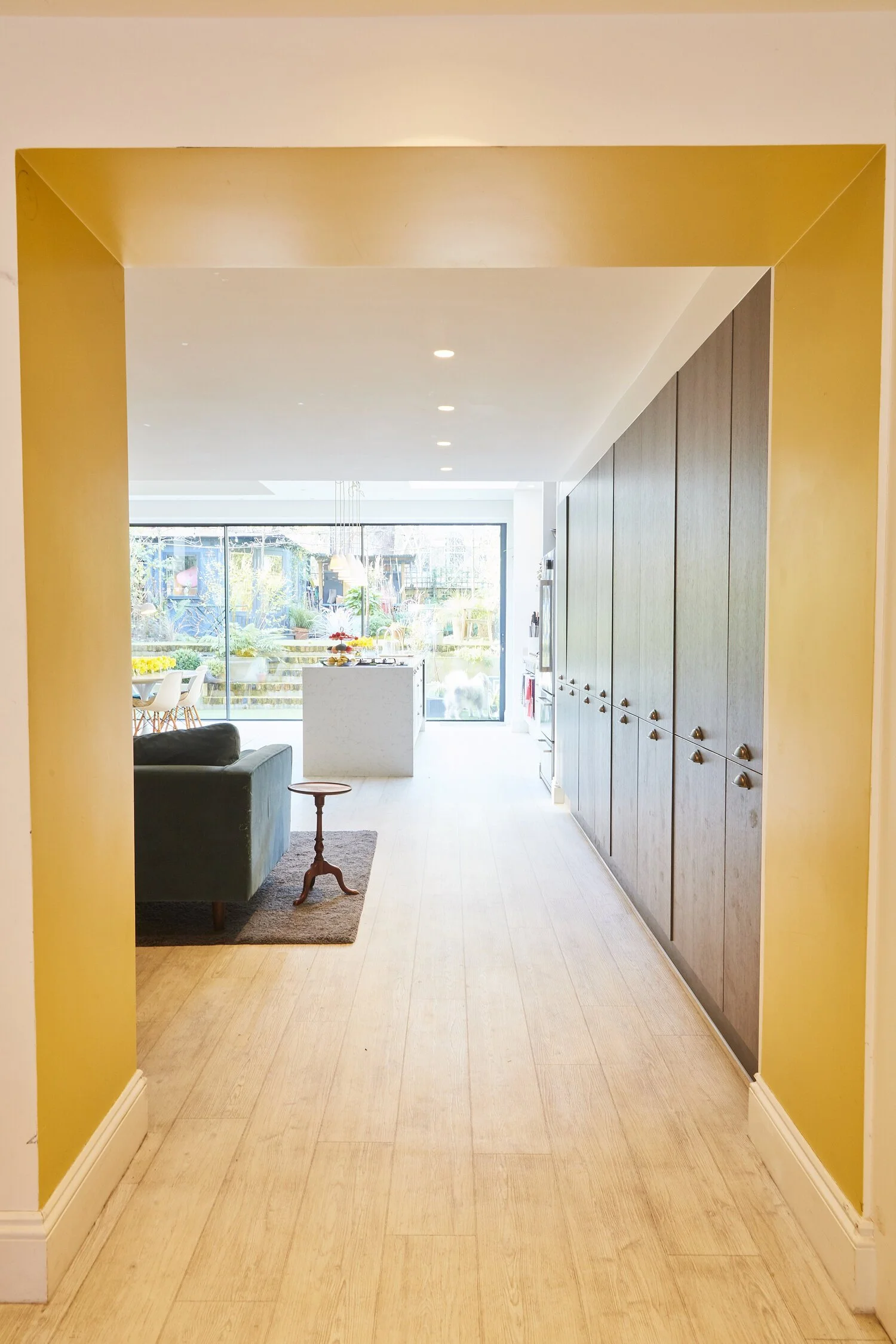 Bright modern kitchen and living space with large glass sliding doors opening to a lush garden.