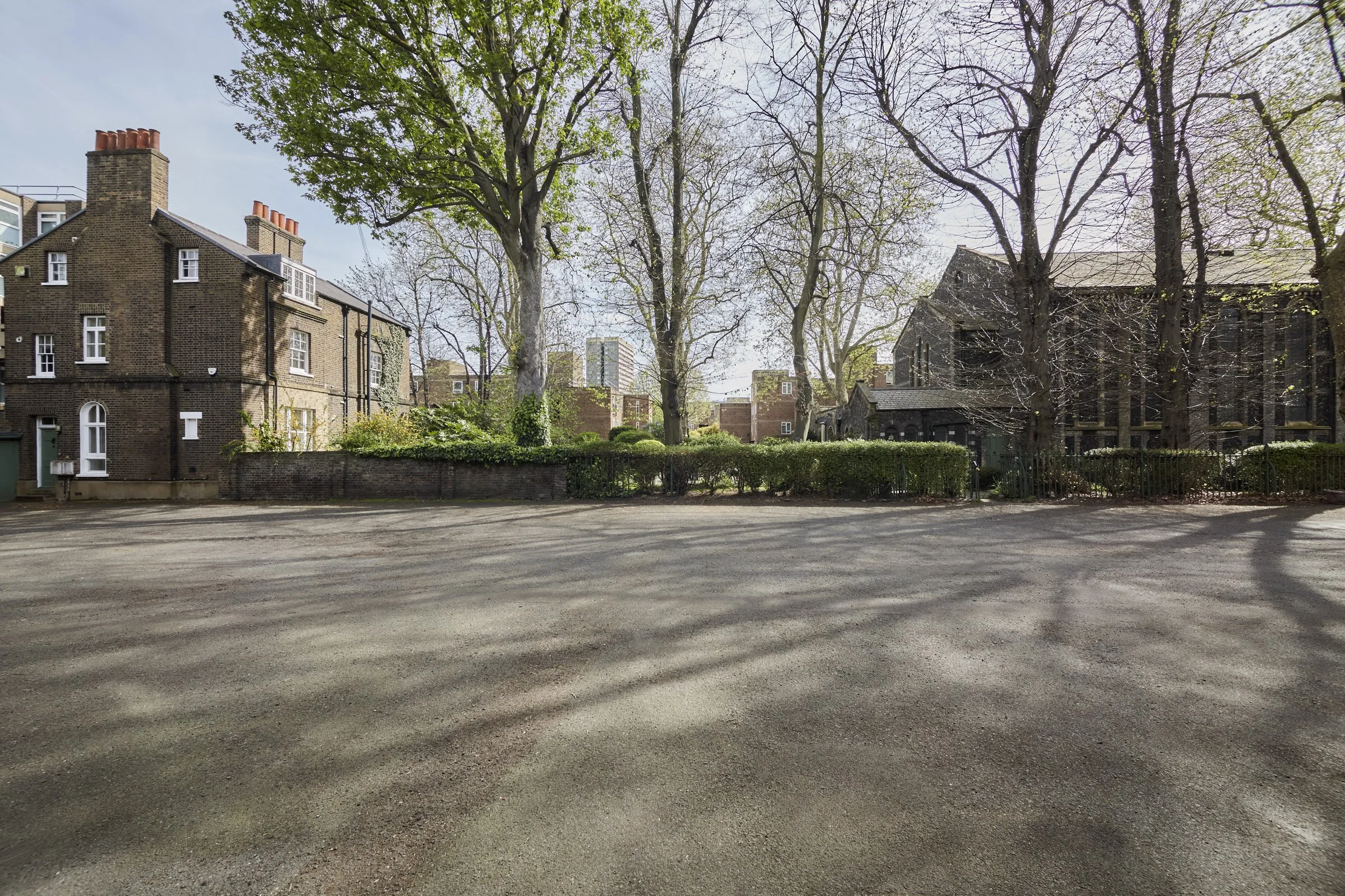 Empty outdoor parking lot with trees and buildings in the background.