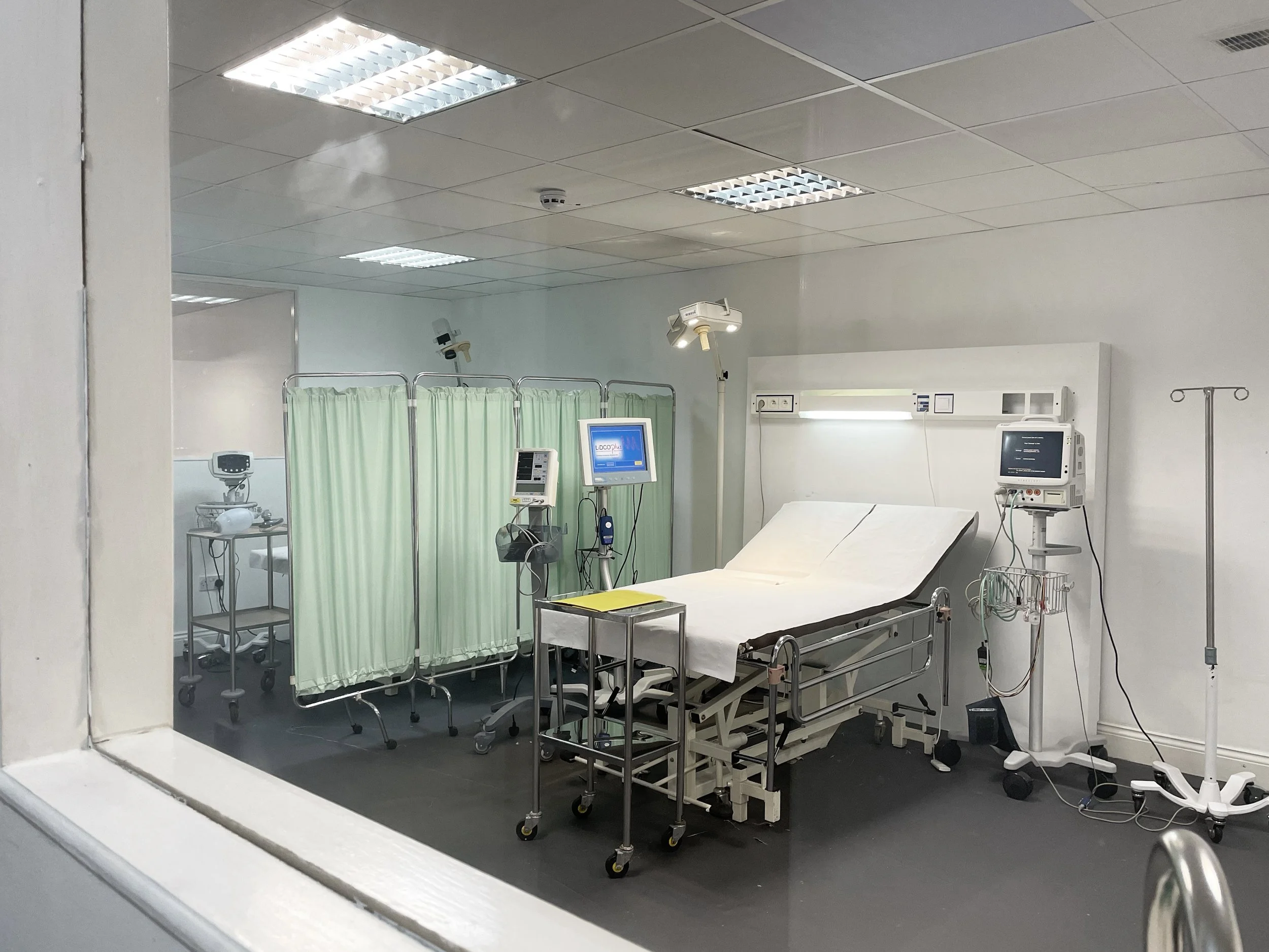 Hospital hospital room with a bed, medical monitors, IV stand, and privacy curtains.