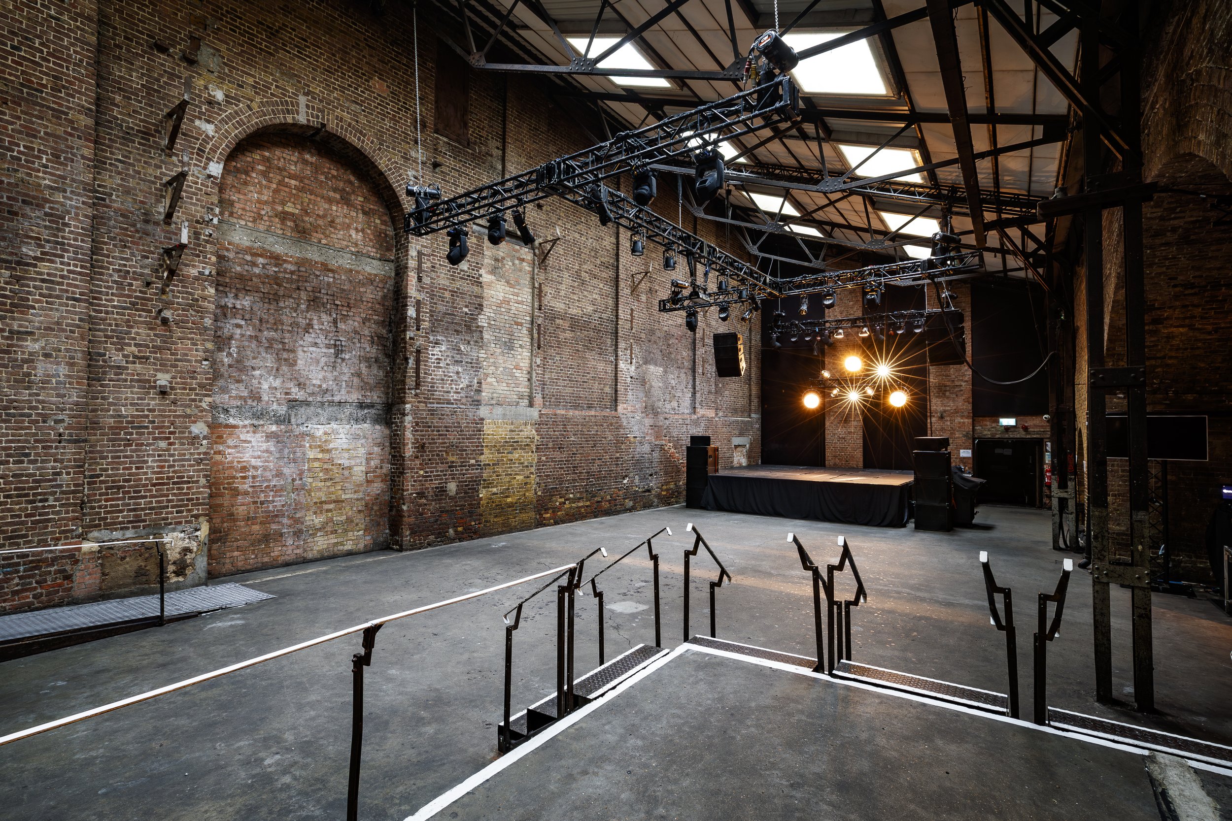 Exposed red brick warehouse event venue with lighting rig, located in East London