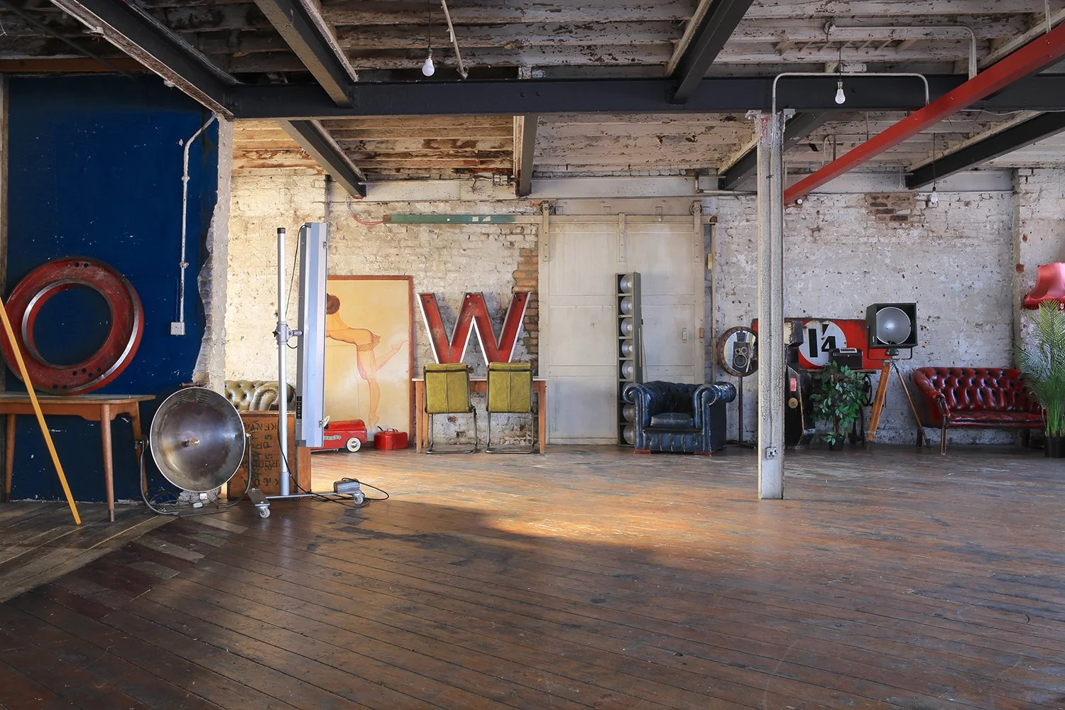 Industrial loft with wooden floor, exposed brick walls, vintage furniture, artwork, and decorative items.