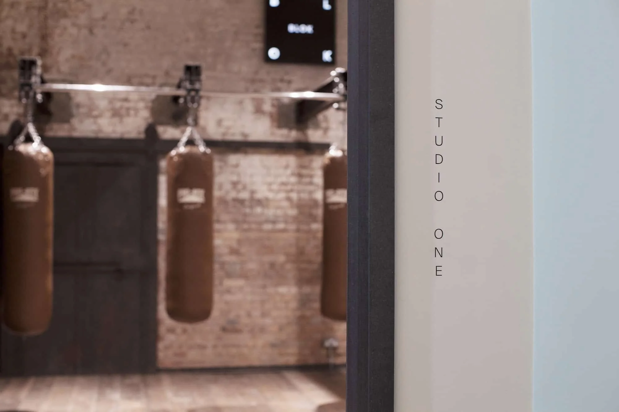A fitness studio with punching bags and a brick wall in the background.