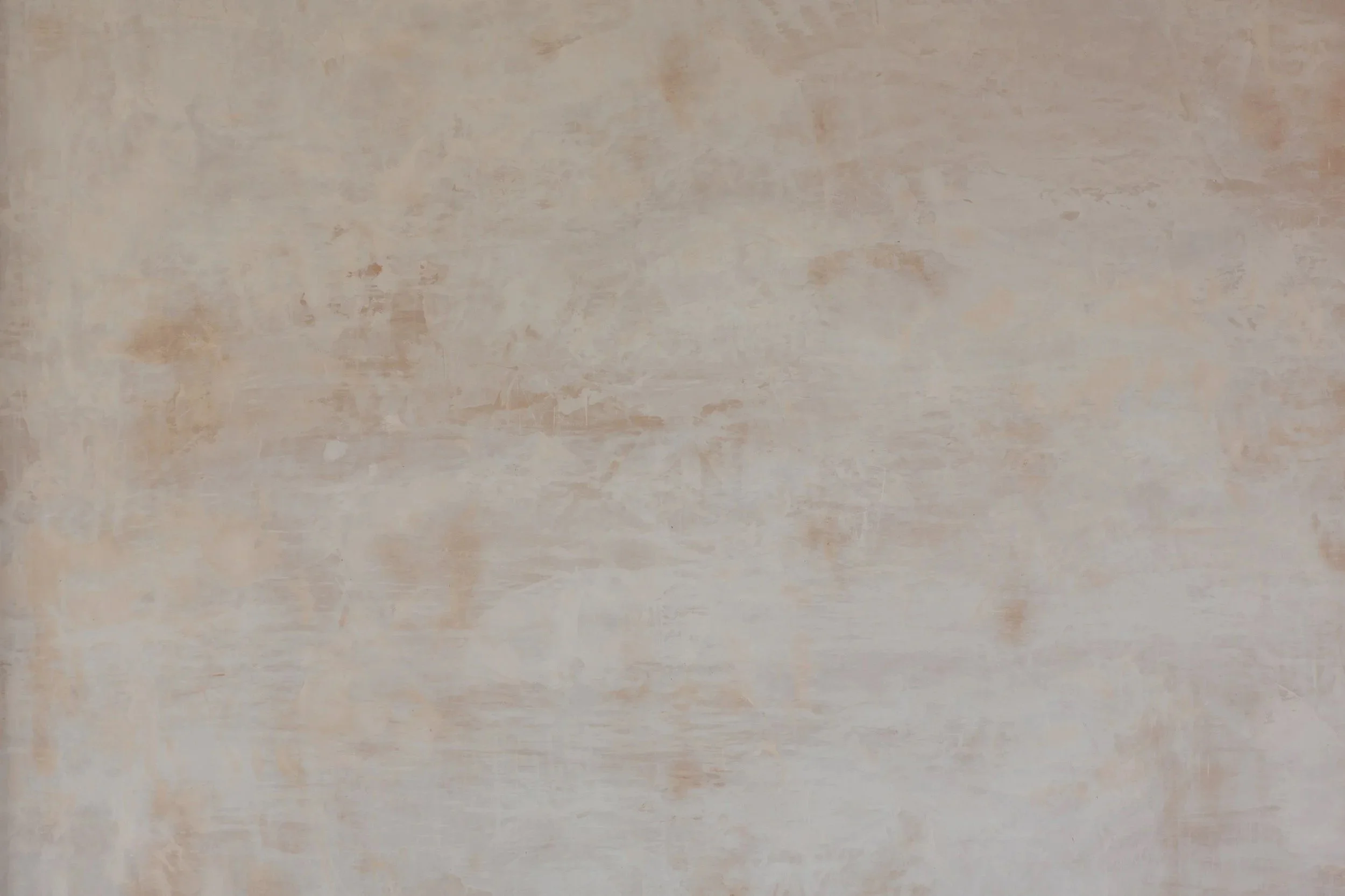 An abstract, textured wall with a mix of beige, light brown, and soft pinkish tones.
