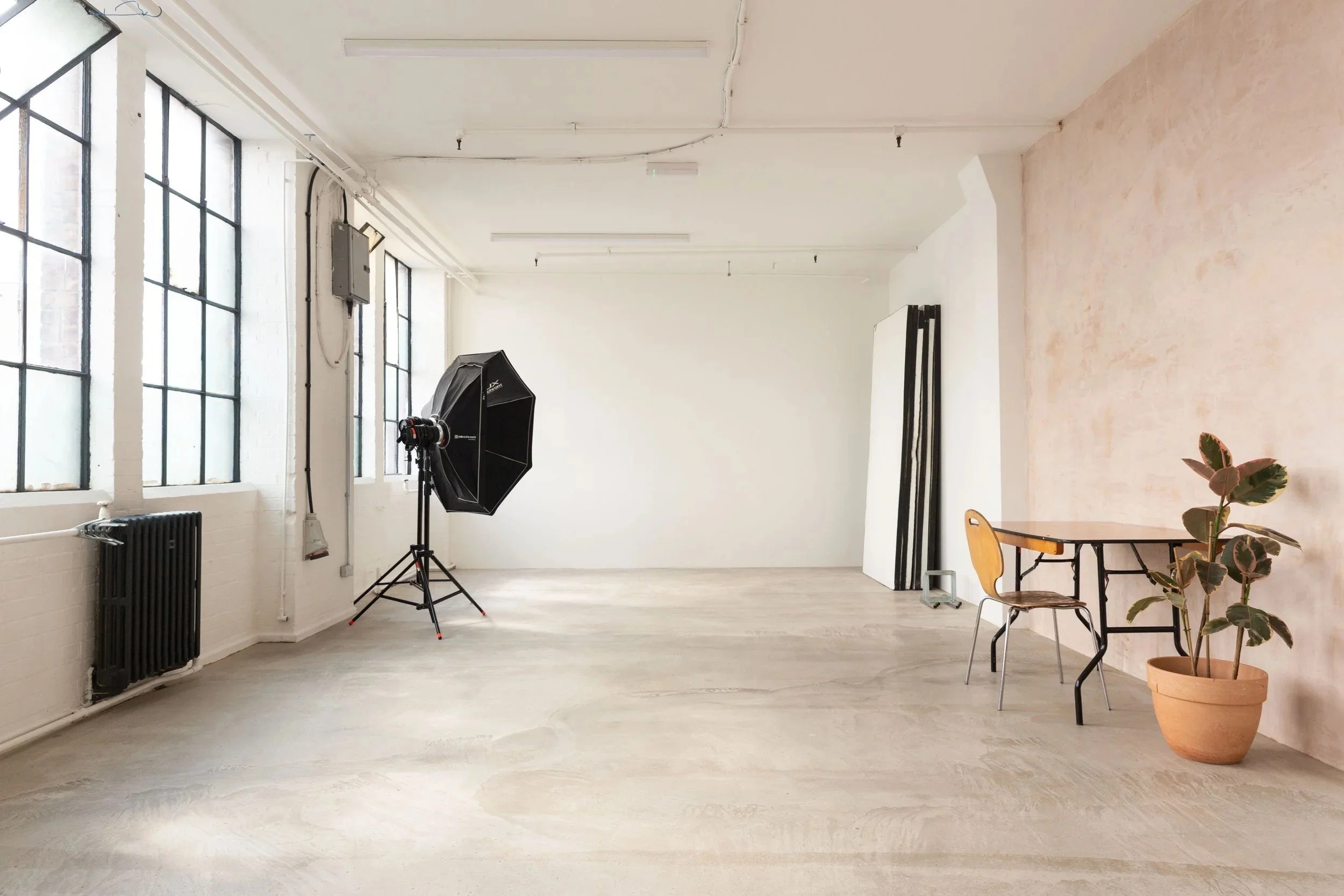 Warehouse photography studio with concrete floor, raw plaster walls and daylight, South London