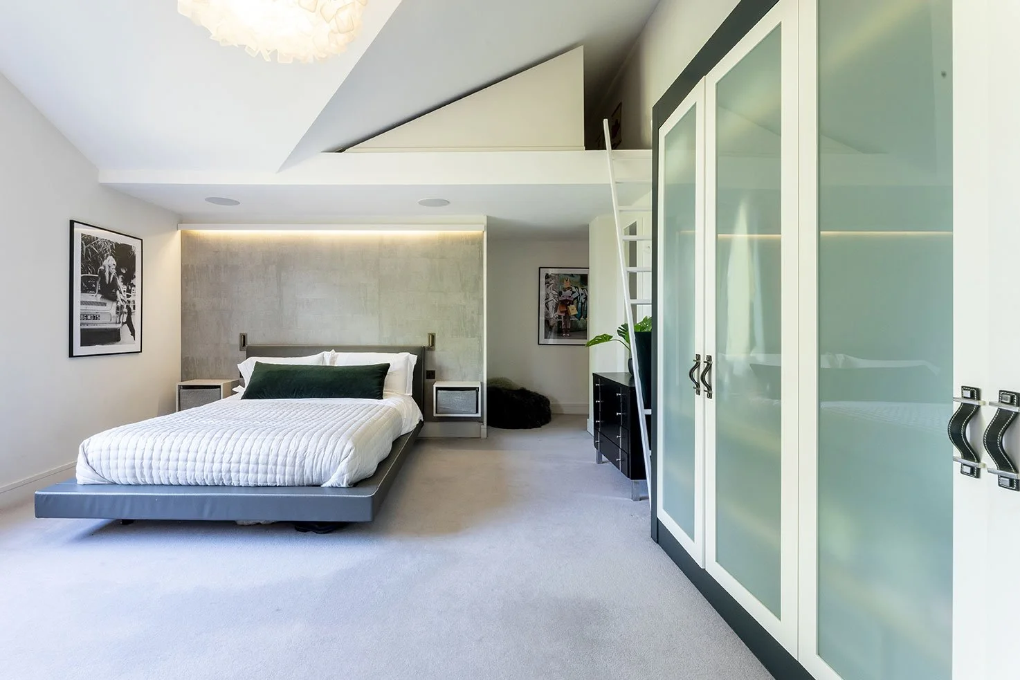 Modern bedroom with bed, black and white artwork, and built-in closet with frosted glass doors.