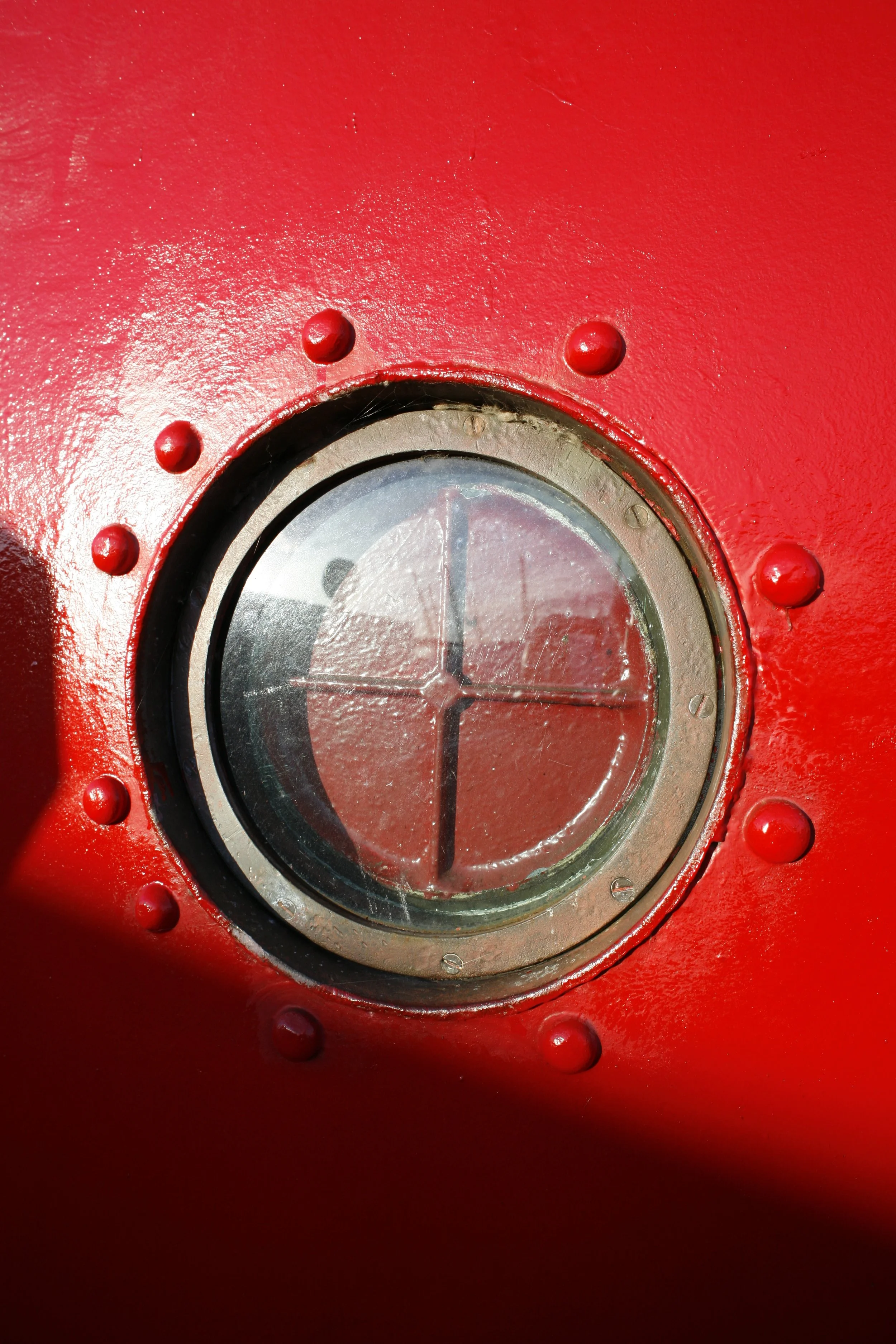 Close-up of a round, glass-covered timer or gauge embedded in a red, textured surface with rivets around it.