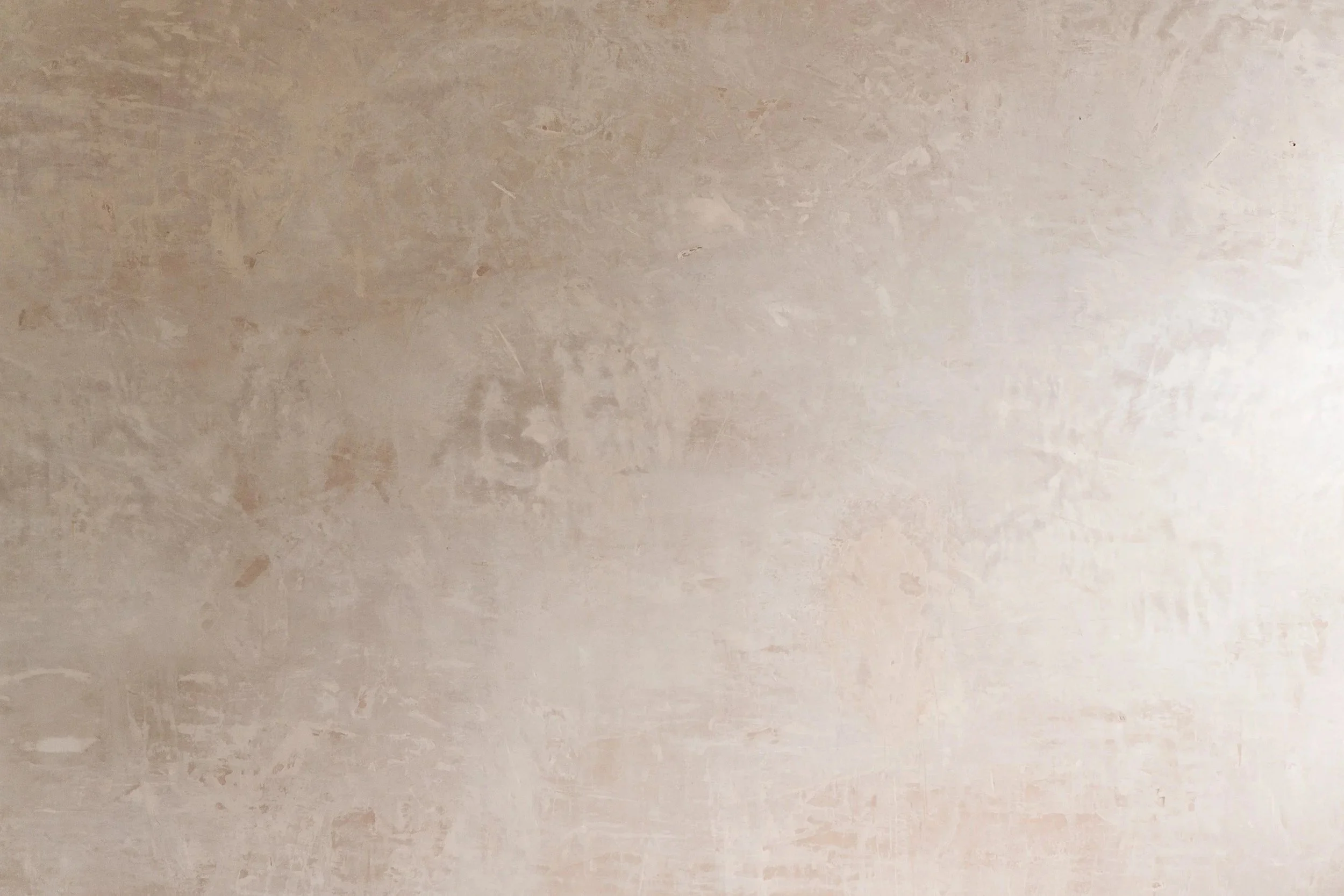 A textured beige wall with patches of worn paint.