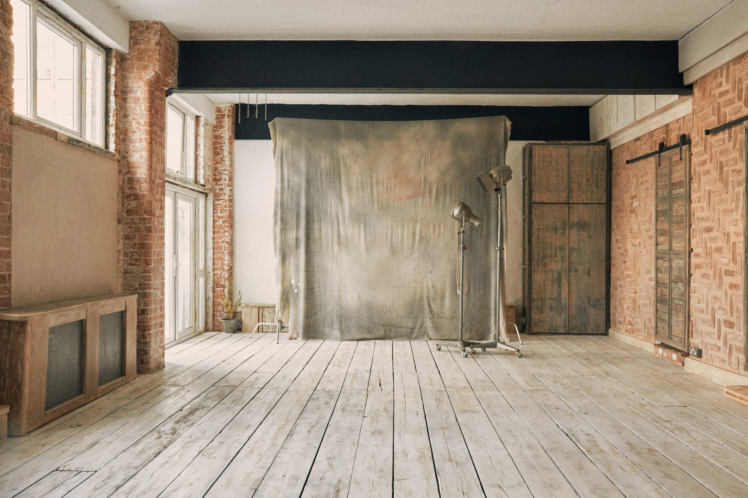 Light wooden flooring, exposed brick and cloth background in warehouse studio in North London