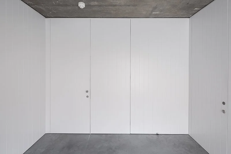 Empty white room with unfinished concrete ceiling and floor.