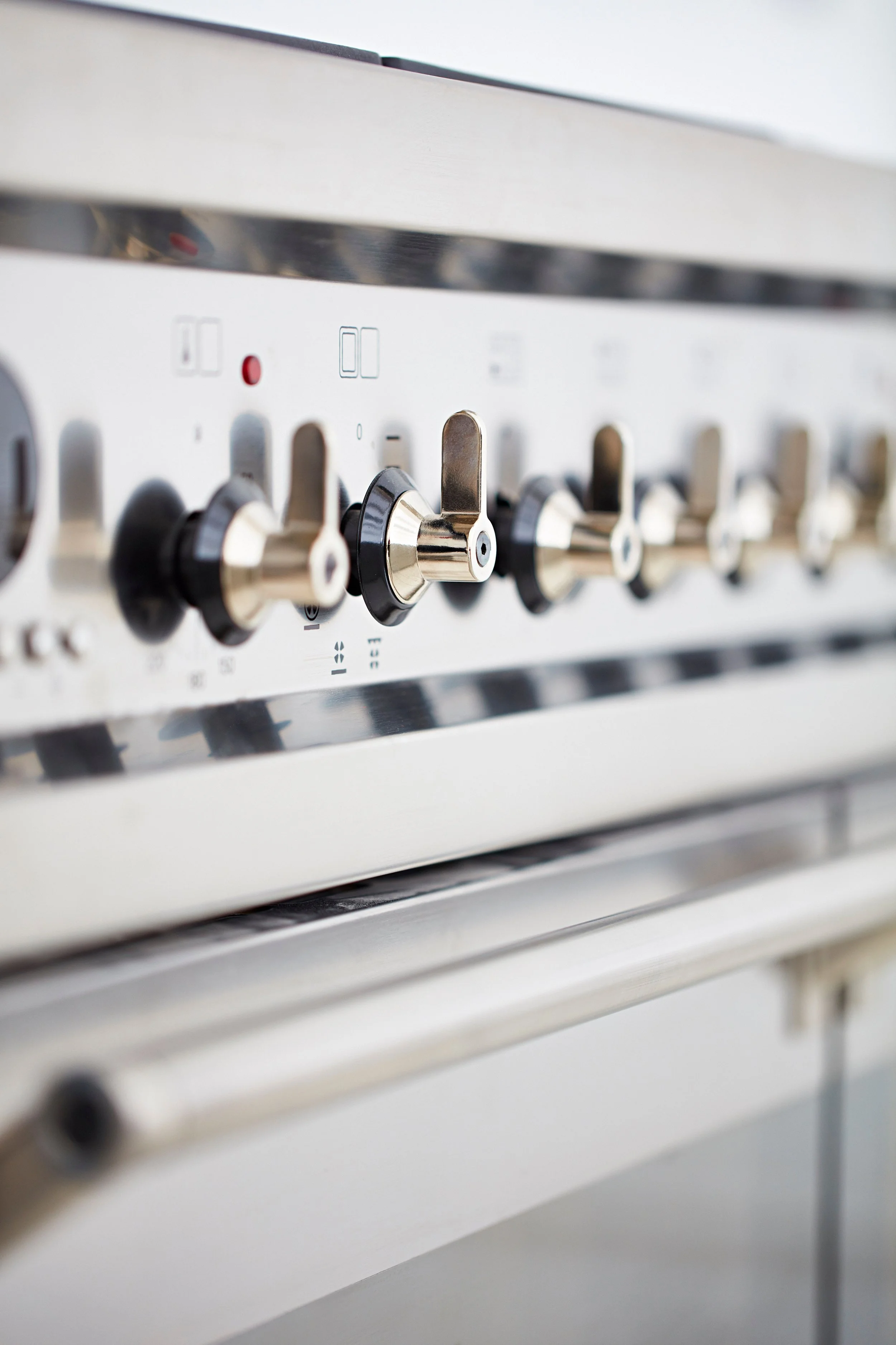 Close-up of a stainless steel gas stove with control knobs and a red indicator light.