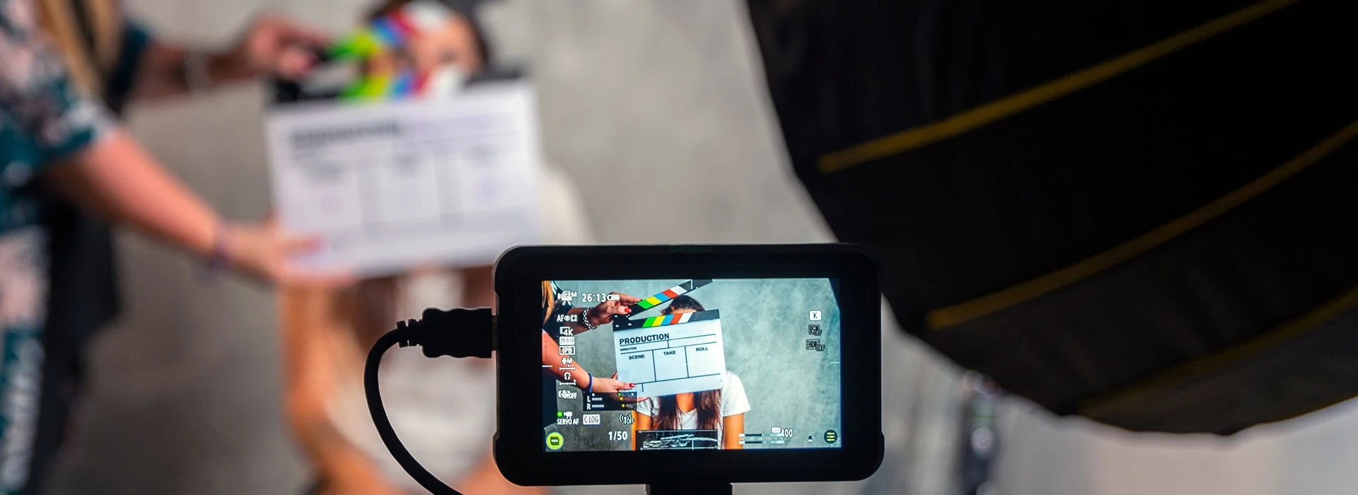 Video production setup with camera monitor, clapperboard, lighting, and interview subject during a corporate documentary shoot.