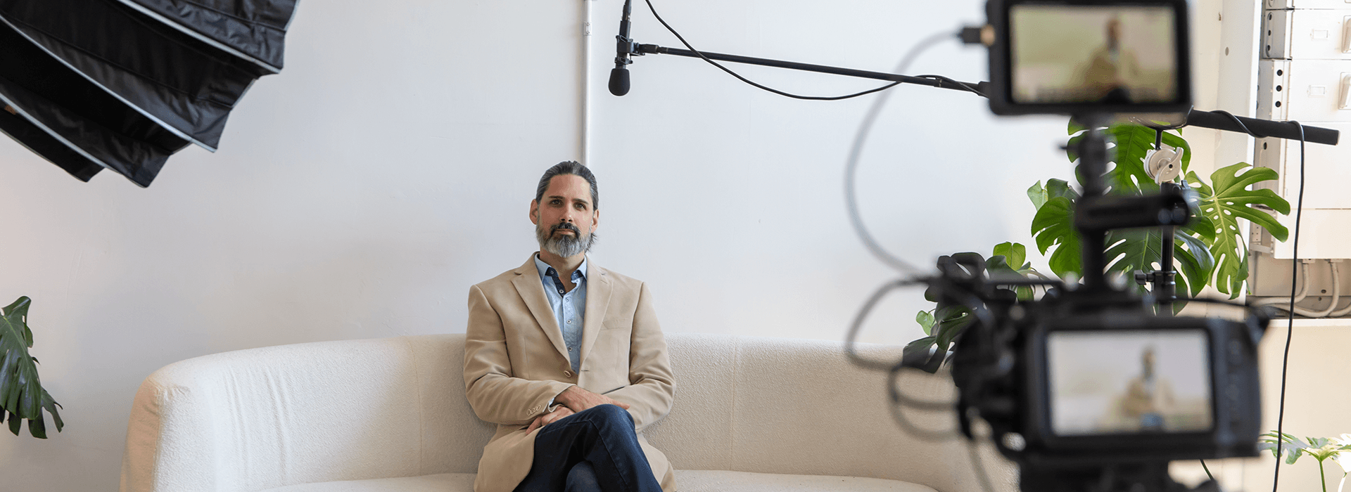 Interview setup for a corporate storytelling video, with a speaker seated on a sofa and cameras, lighting, and boom microphone visible