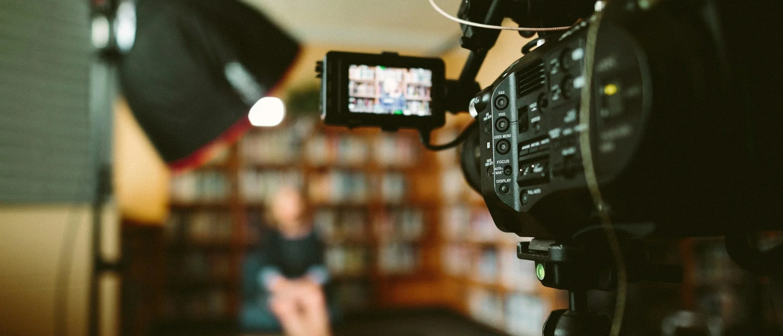 Professional video camera filming an interview subject in a softly lit indoor setting