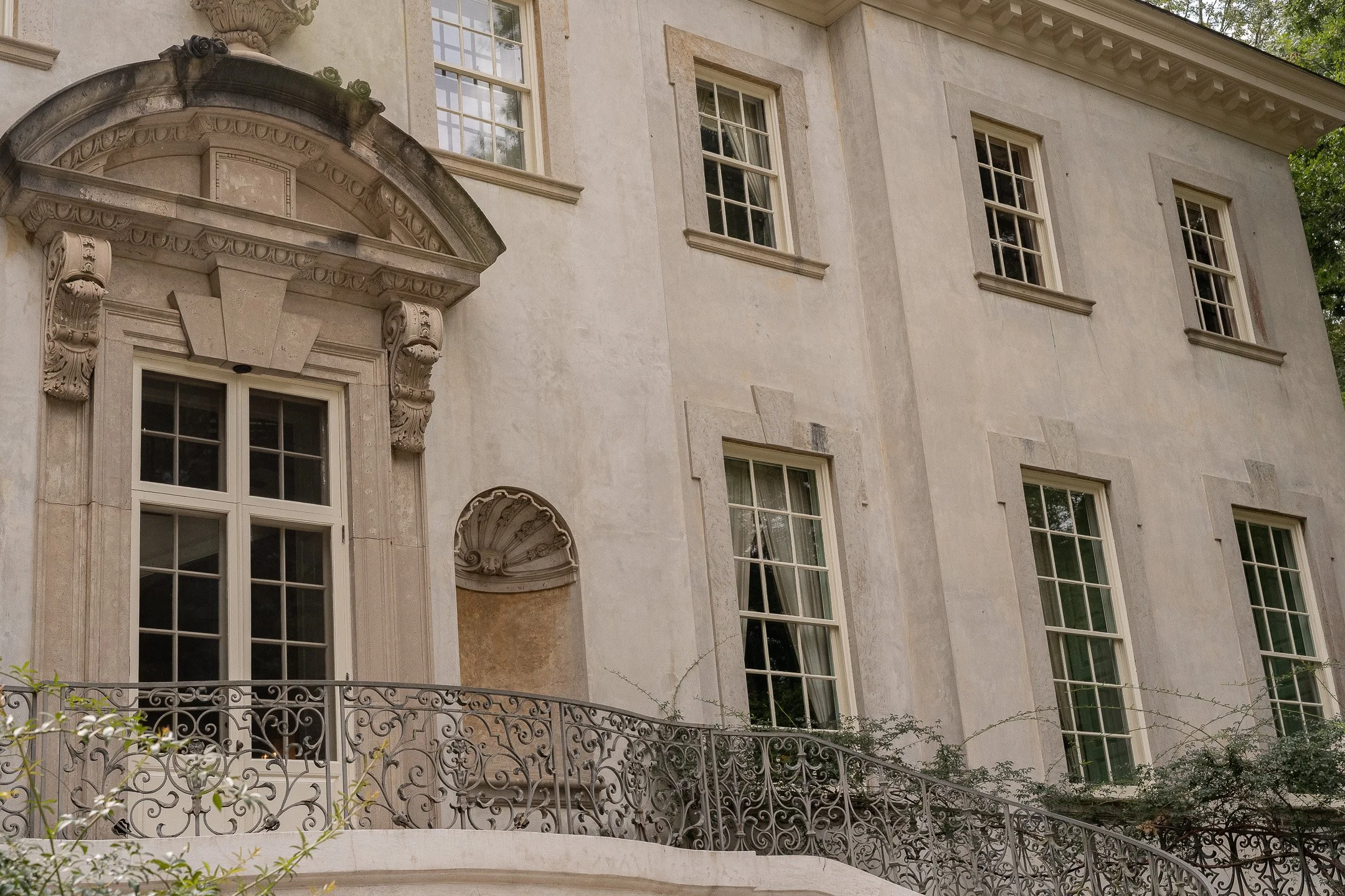 Classic European-style architecture with ornate window and balcony, decorative stonework, and iron railing.