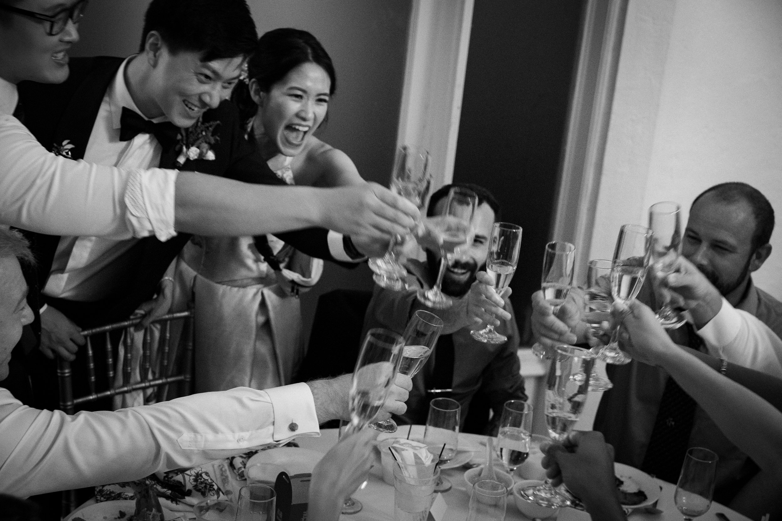 Group of people raising glasses for a toast at a celebration or gathering, smiling and enjoying the moment.