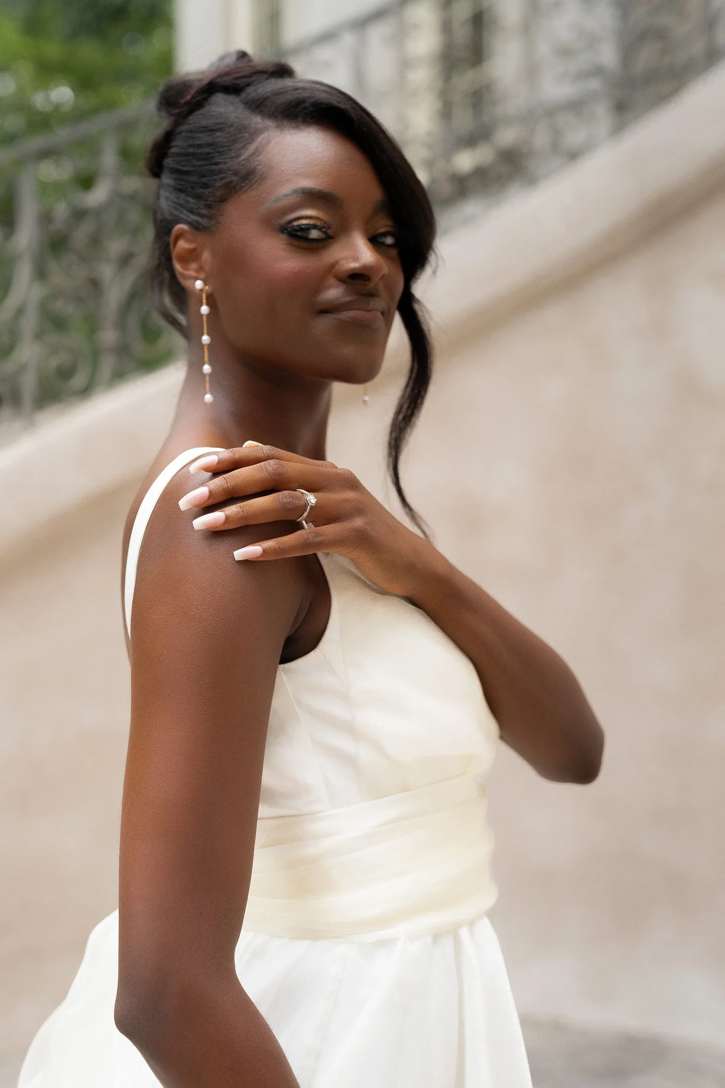 Woman in white dress showing engagement ring while smiling