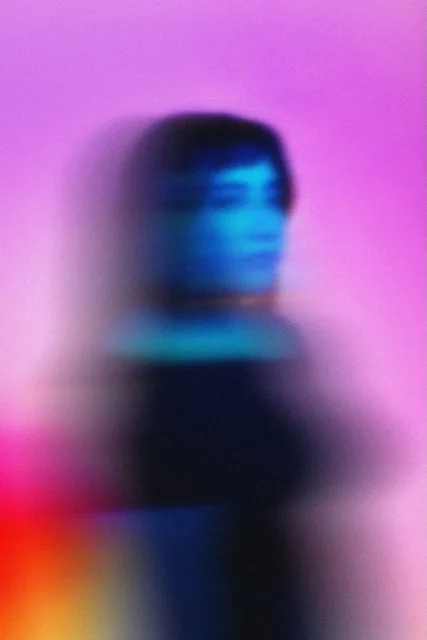 Portrait of a blurred woman in blue, on a pink, orange and yellow background