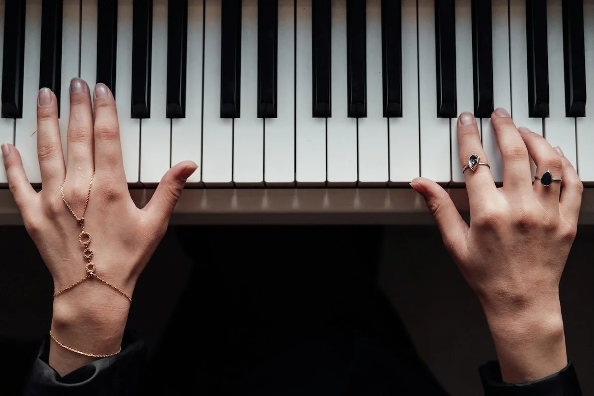 Woman's hands with jewelry laying on a piano