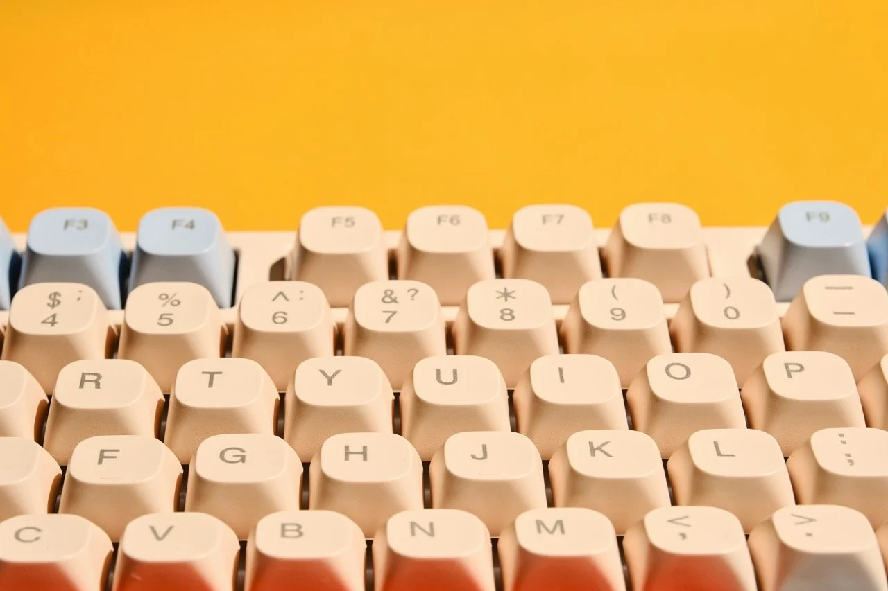 Close-up of a retro-style computer keyboard with beige keys against a yellow background.