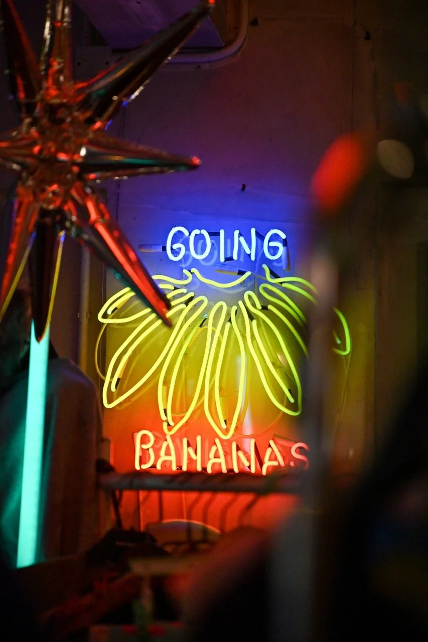 Neon sign reading 'Going Bananas' with a banana graphic in yellow, blue, and red colors.