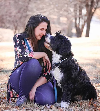 Service dog handler crouching down next to black and white service dog