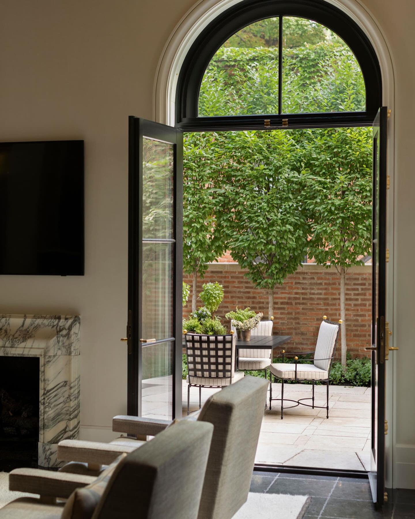 Inside-Out / It&rsquo;s so rare and special to have spaces in a Chicago home with natural light from three sides. This Lincoln Park Family Room has a series of five arch top French doors which lead to a picturesque urban garden. #designenmasse
