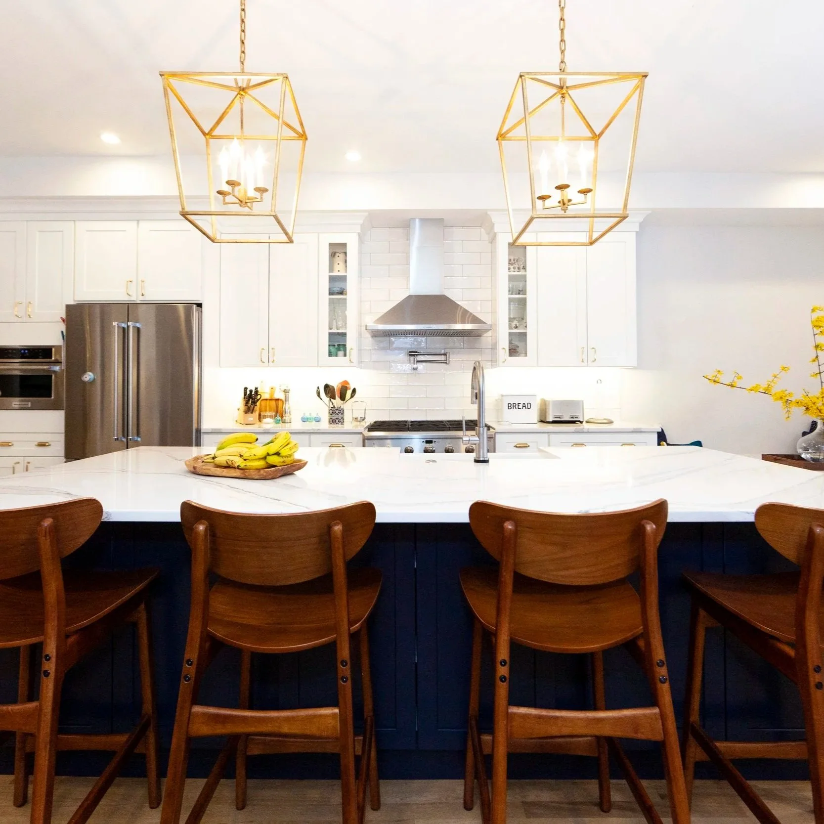 White kitchen with navy island, gold lantern pendants, and eat-in banquette nook, Hill East DC renovation