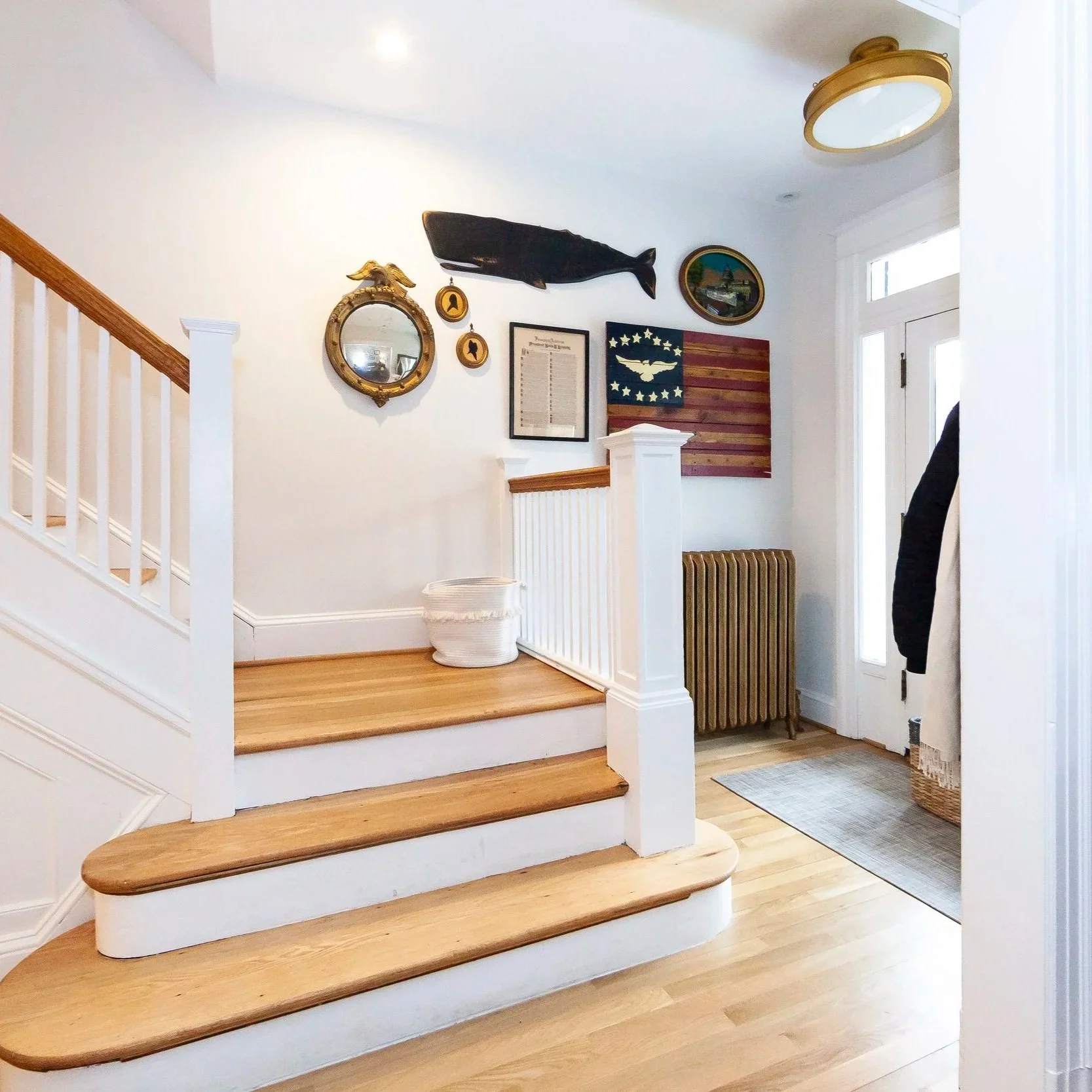 Foyer with wood stair treads, nautical gallery wall, and brass flush mount light, DC interior design