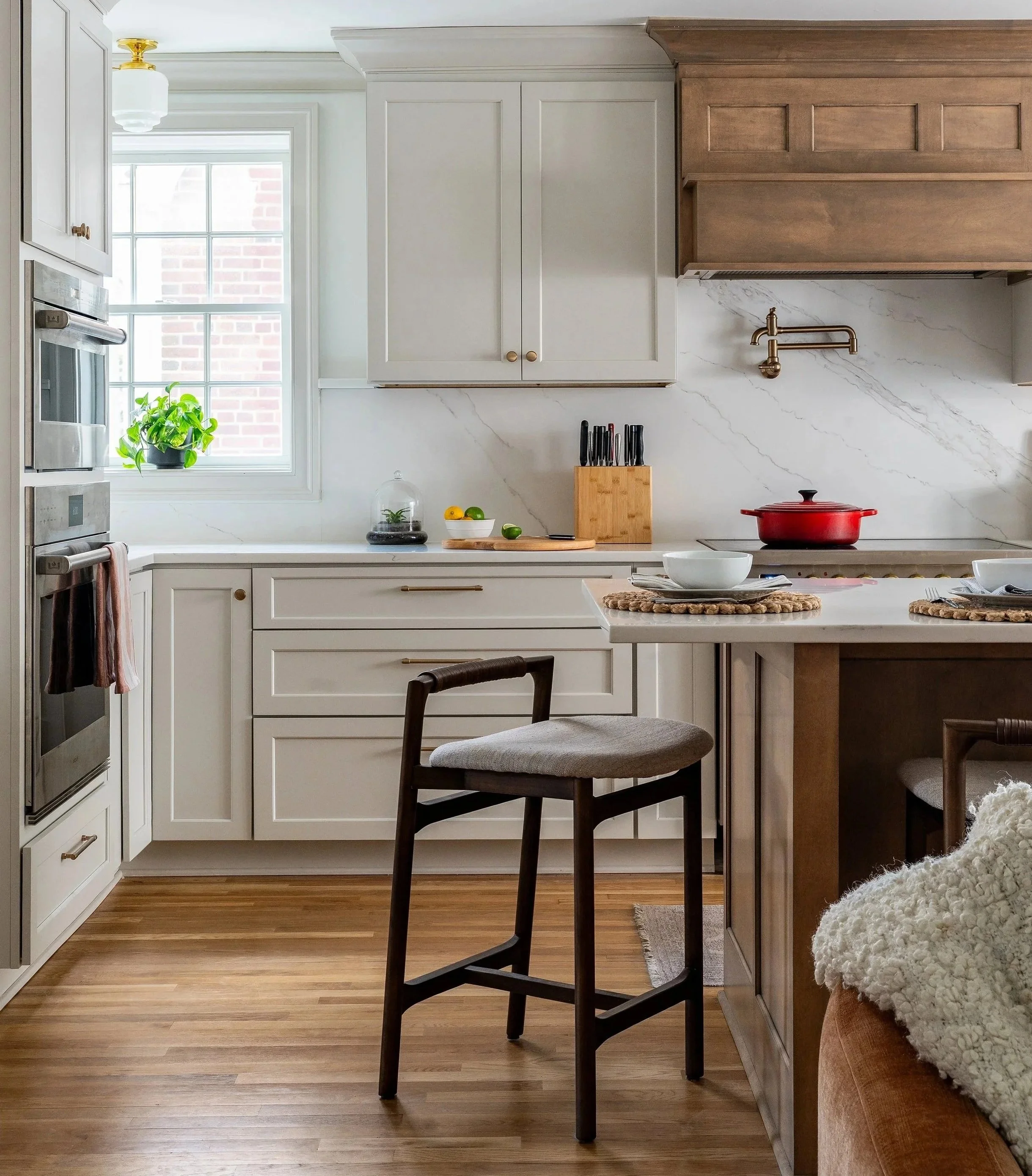 a counter stool in a kitchen iland that is made of wood. White kitchen cabinets are in the background.