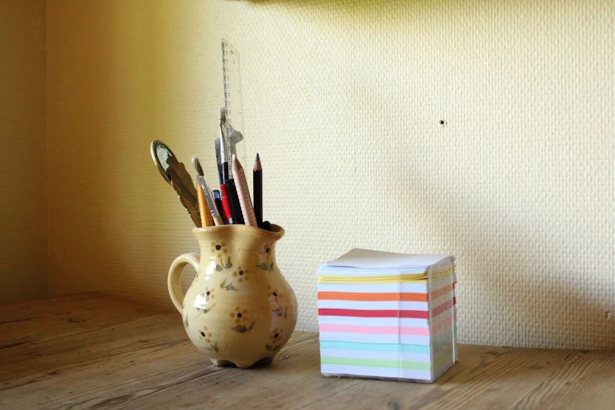 notepapers and a jug of pens on Creators Process coaching desk