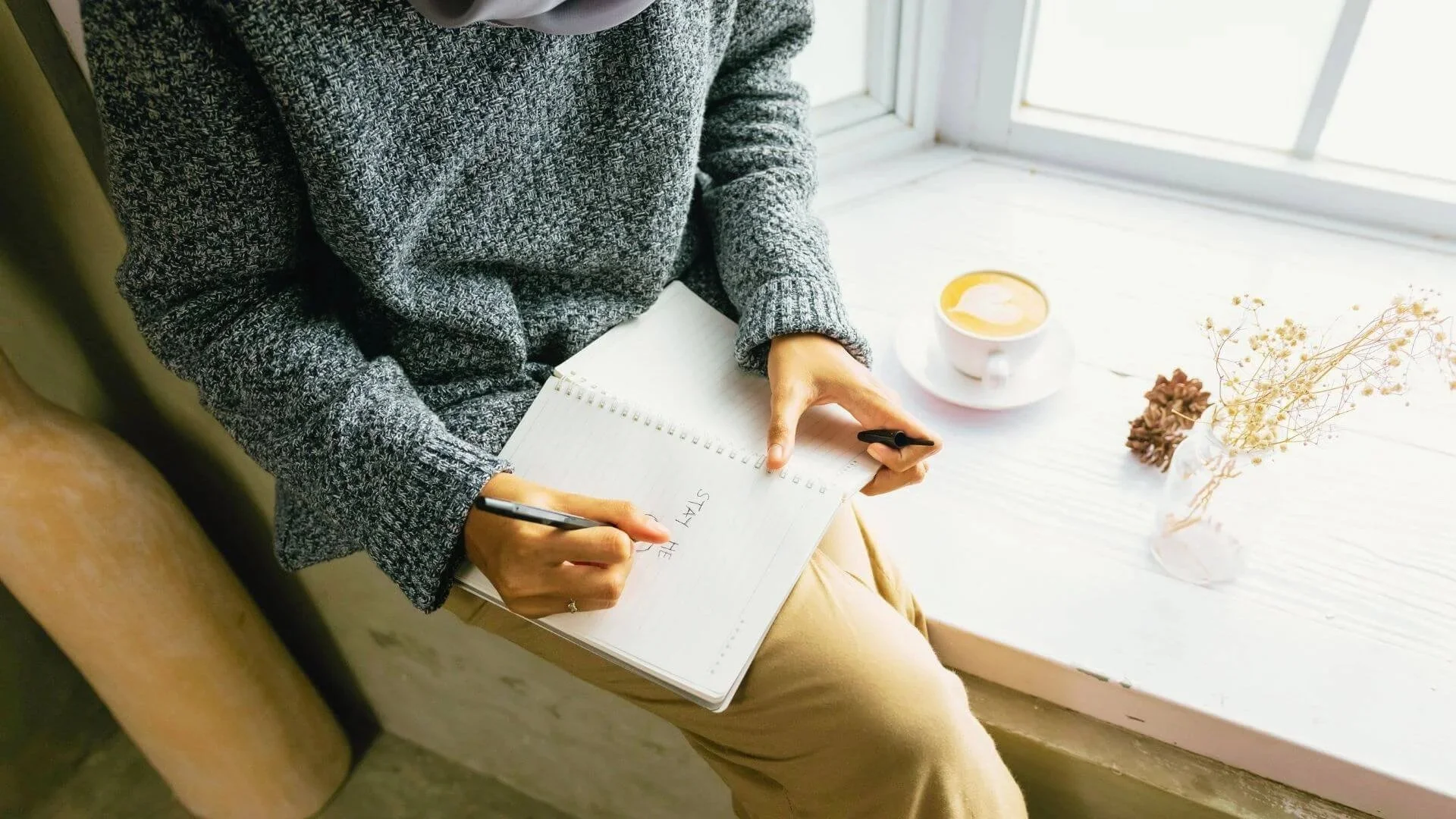 woman sitting by window writing notes