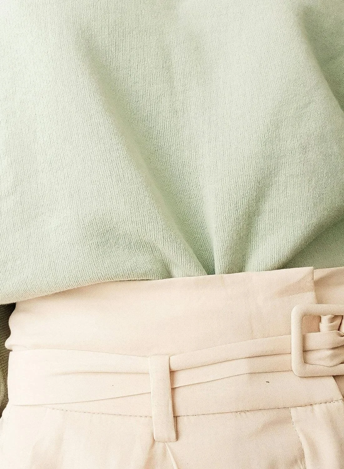 close up of woman in green top and beige trousers