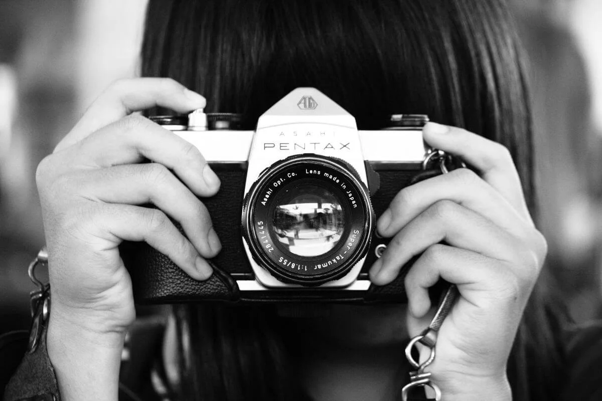 black and white of woman holding a camera representing being creative